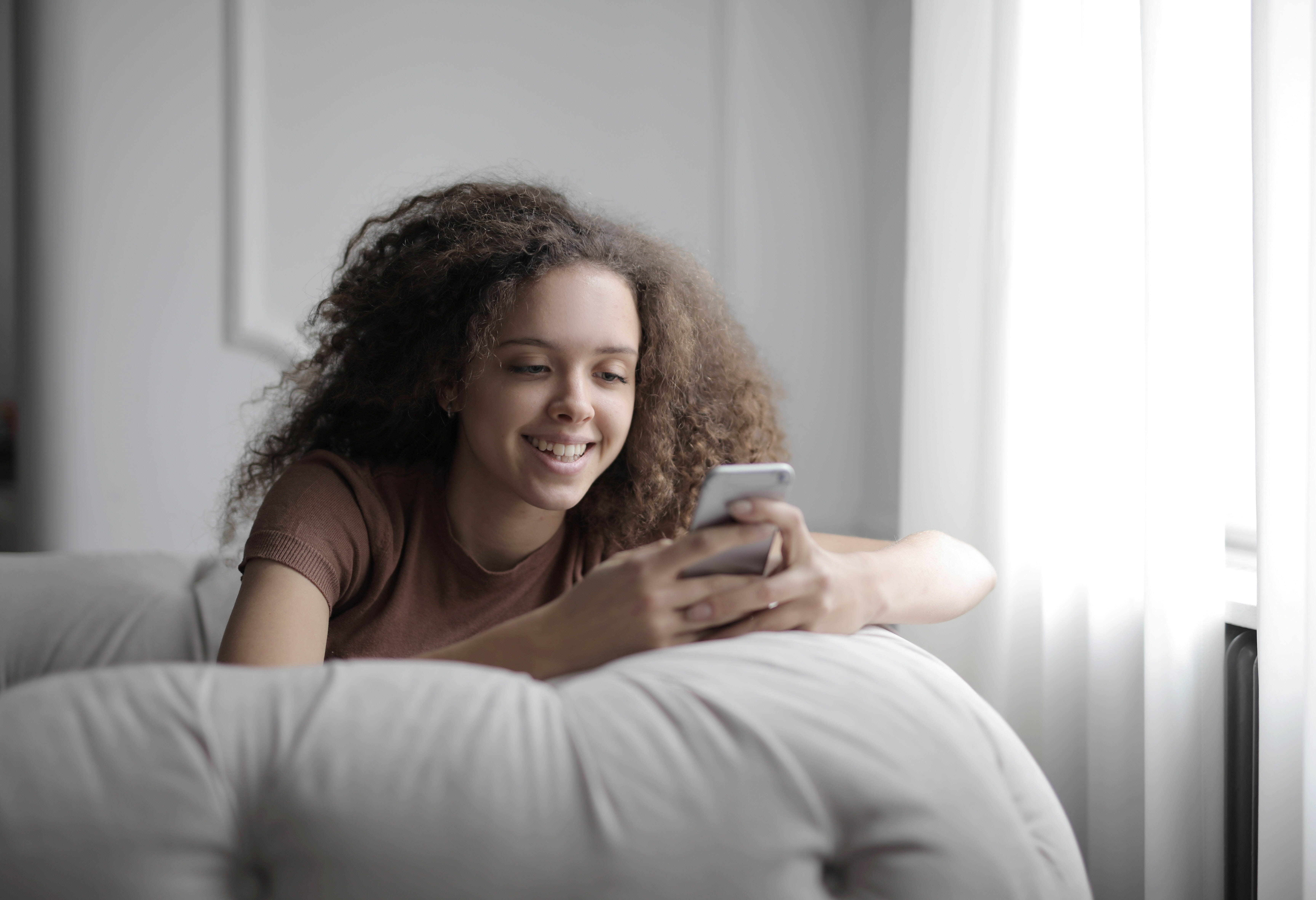 young woman holding phone on couch