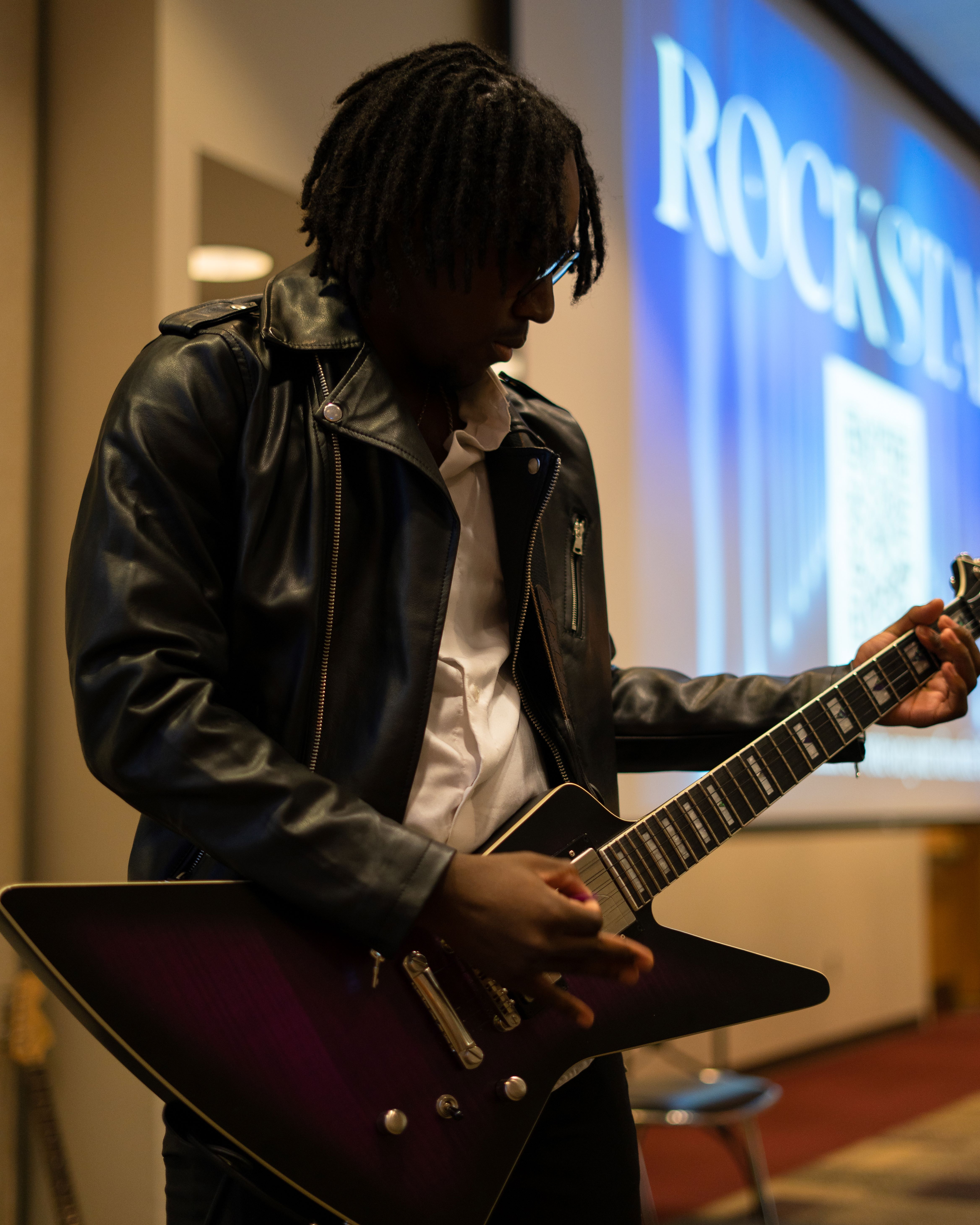 Man playing guitar on stage at fashion show