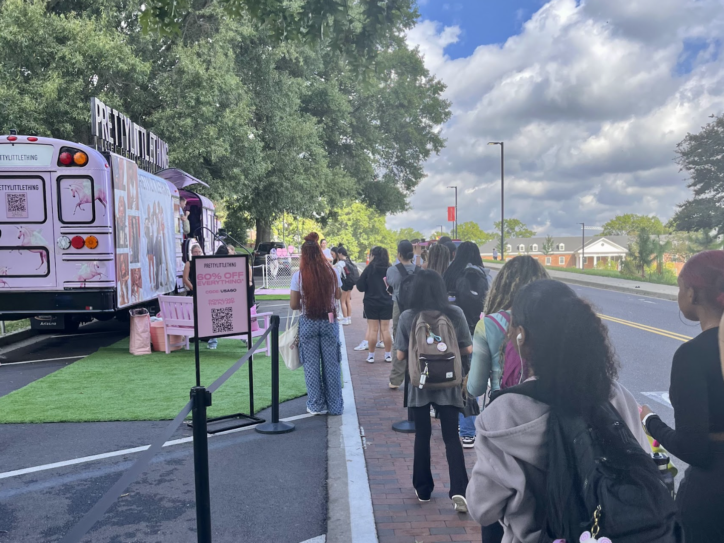 Line of students along the street leads up to pink PrettyLittleThing pop-up bus