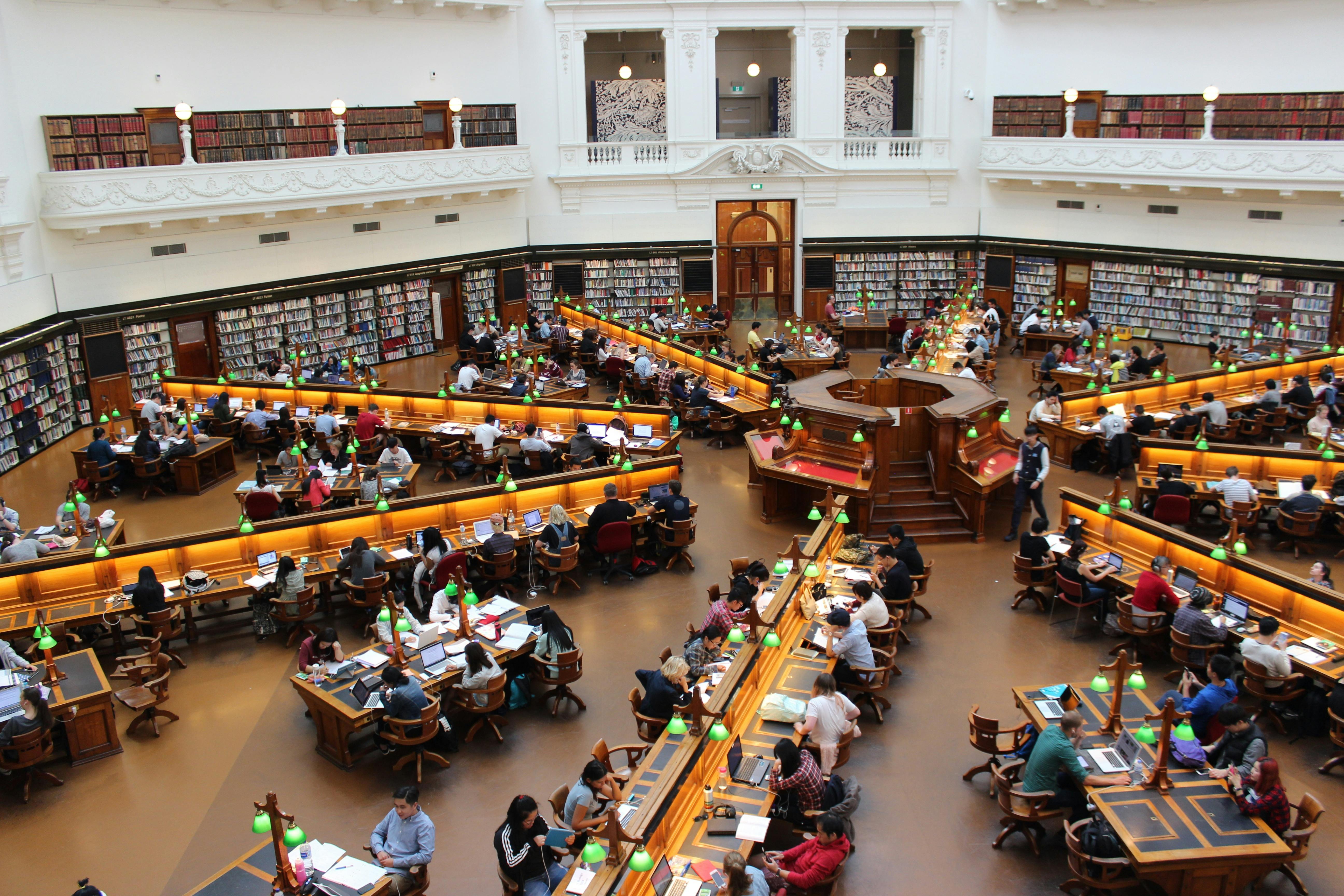 Students sitting in a library and studying around tables