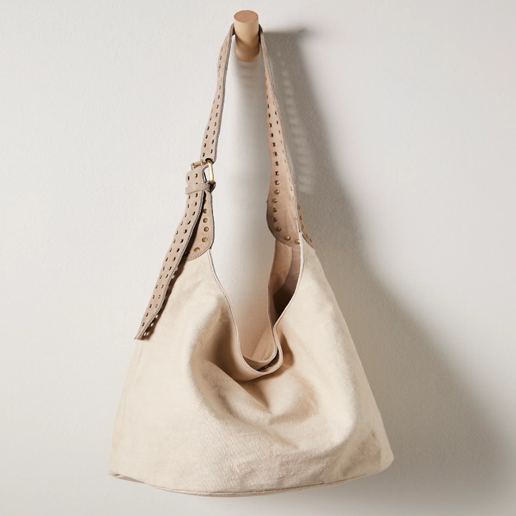 A tan bag hanging on a hook with a white background