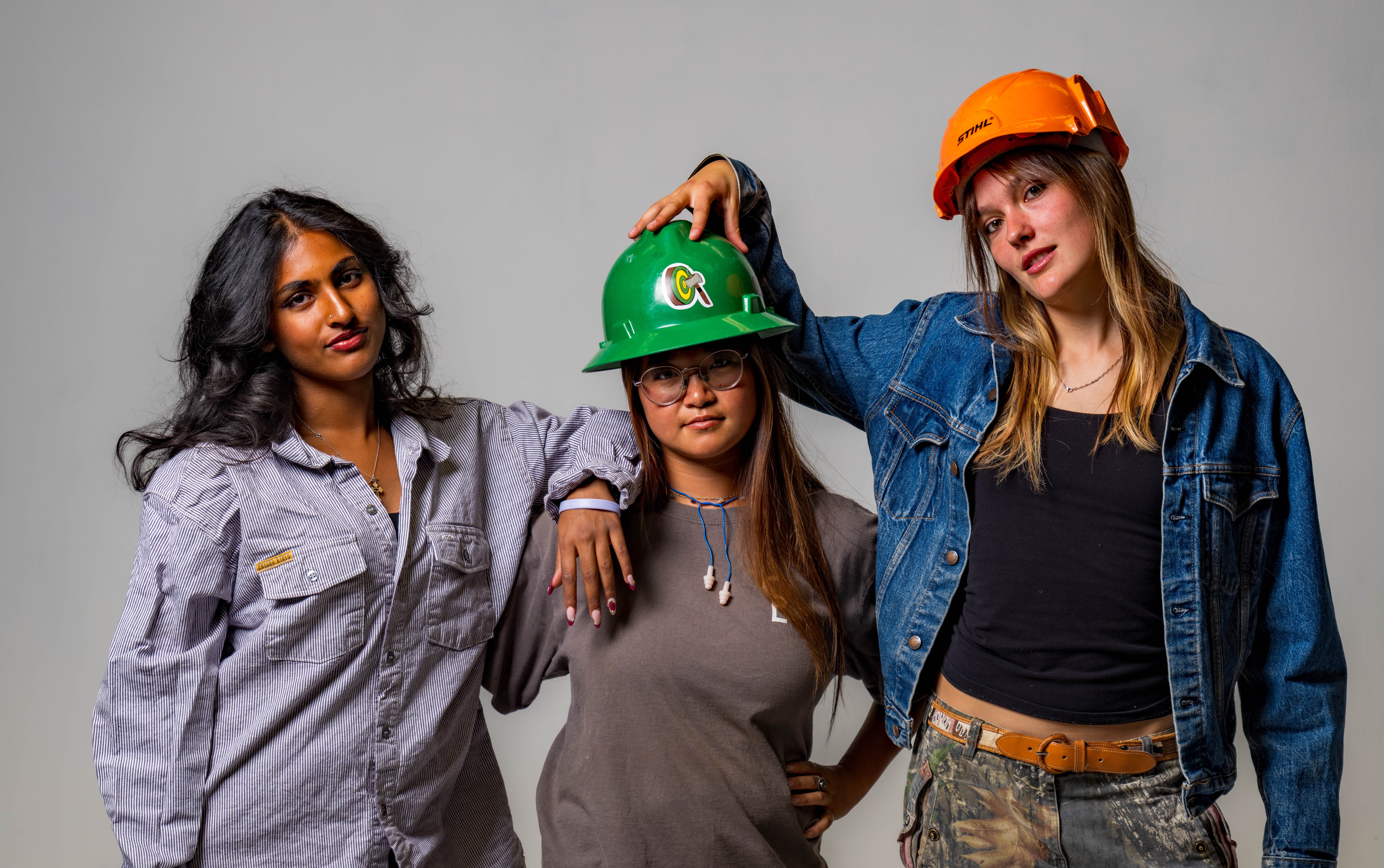 Three women dressed in logging gear in a photo studio