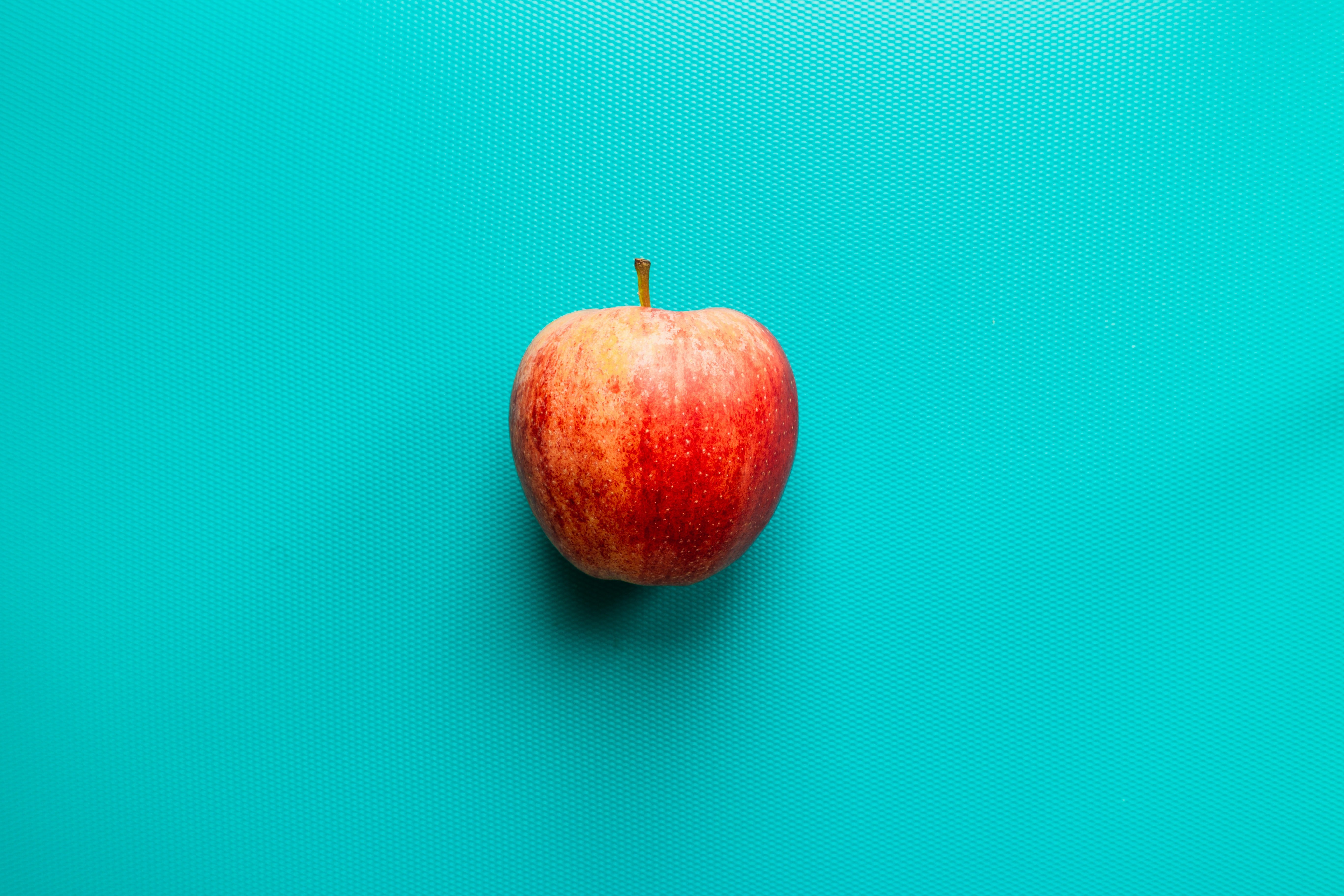 apple on blue surface by Louis Hansel
