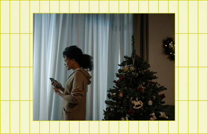 Woman sad on the phone next to a christmas tree.