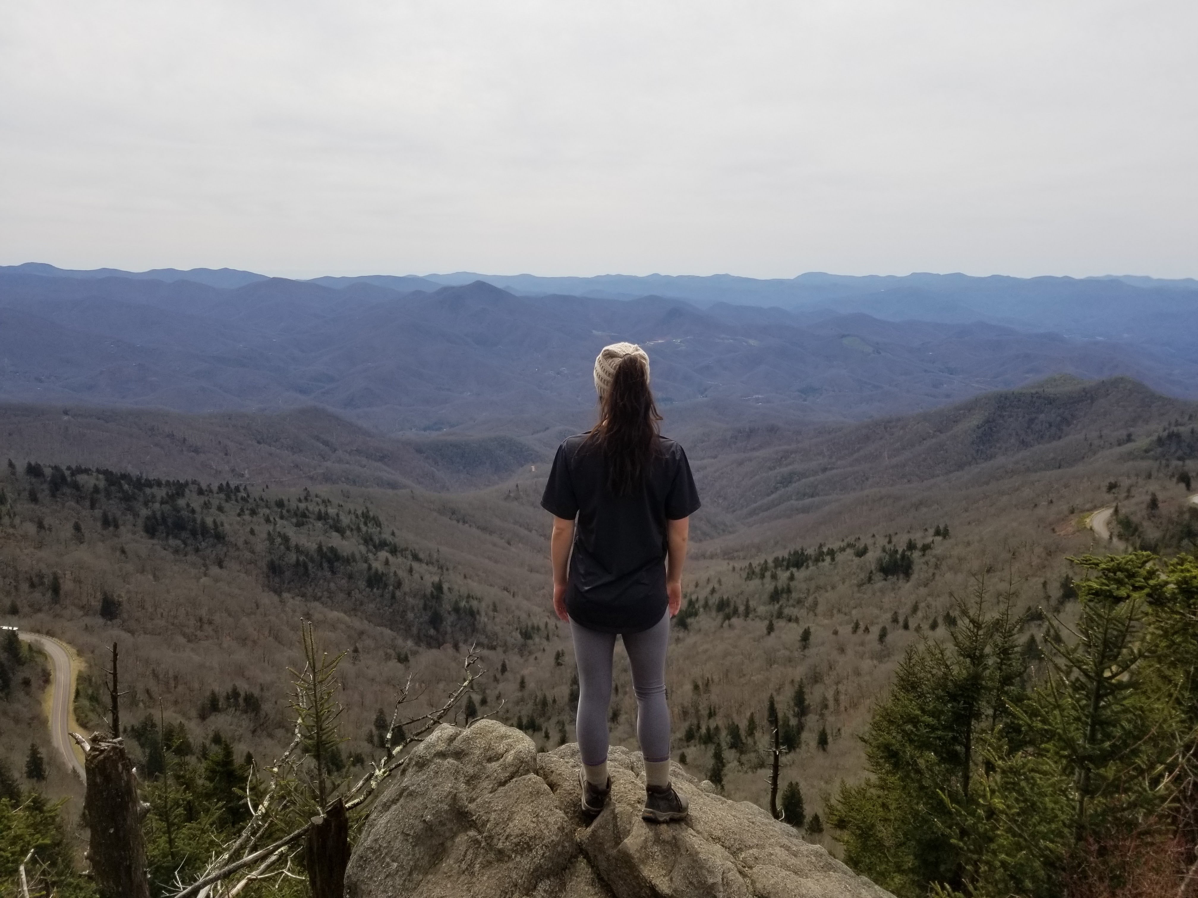 standing on cliff with mountains in view