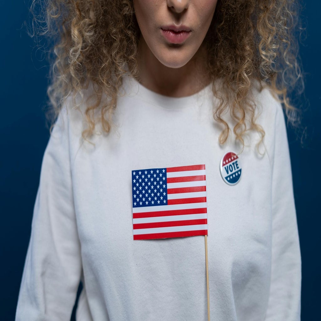 woman with an american flag sweater and vote button