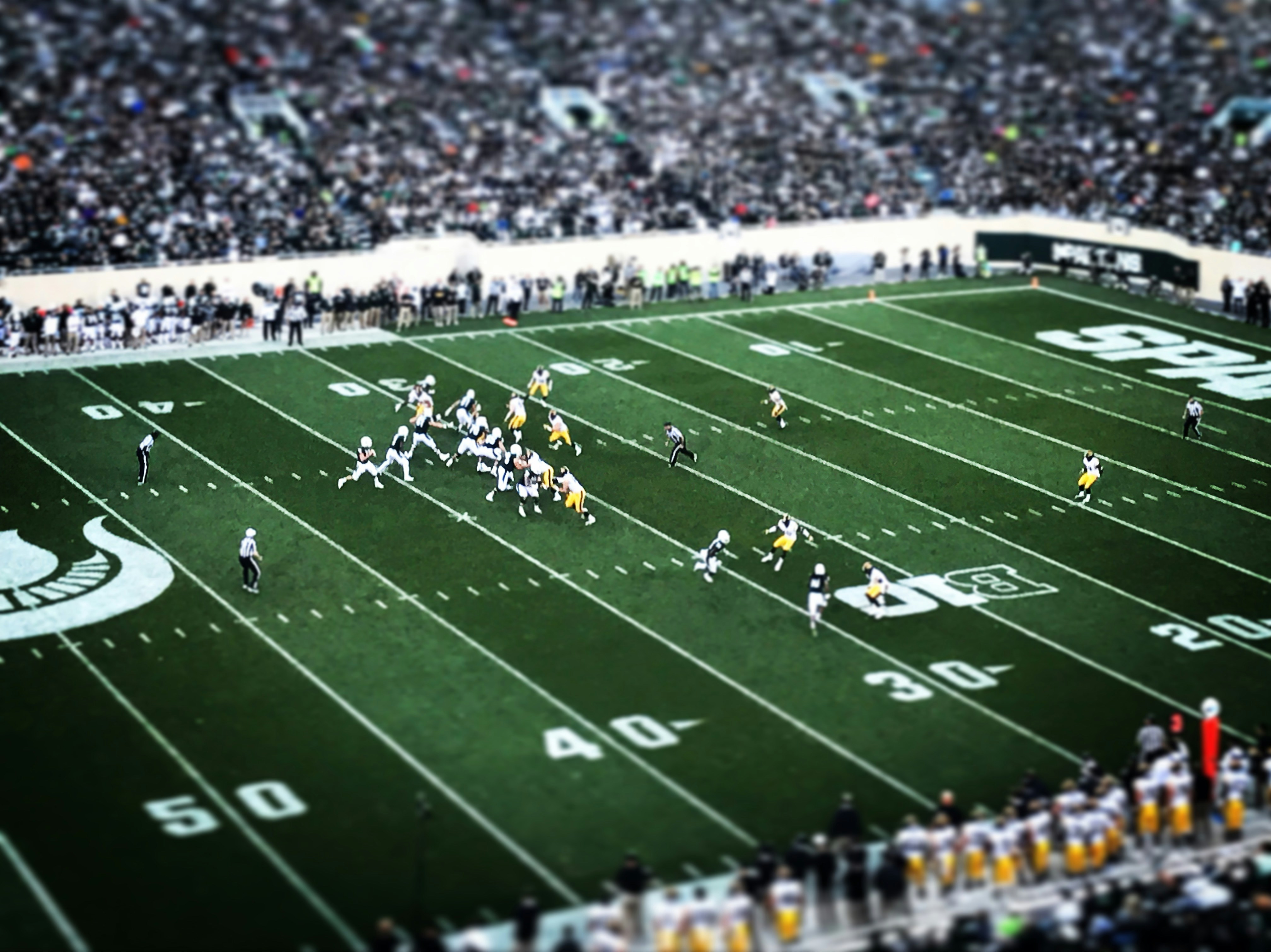 Football players playing on the field with crowd cheering.