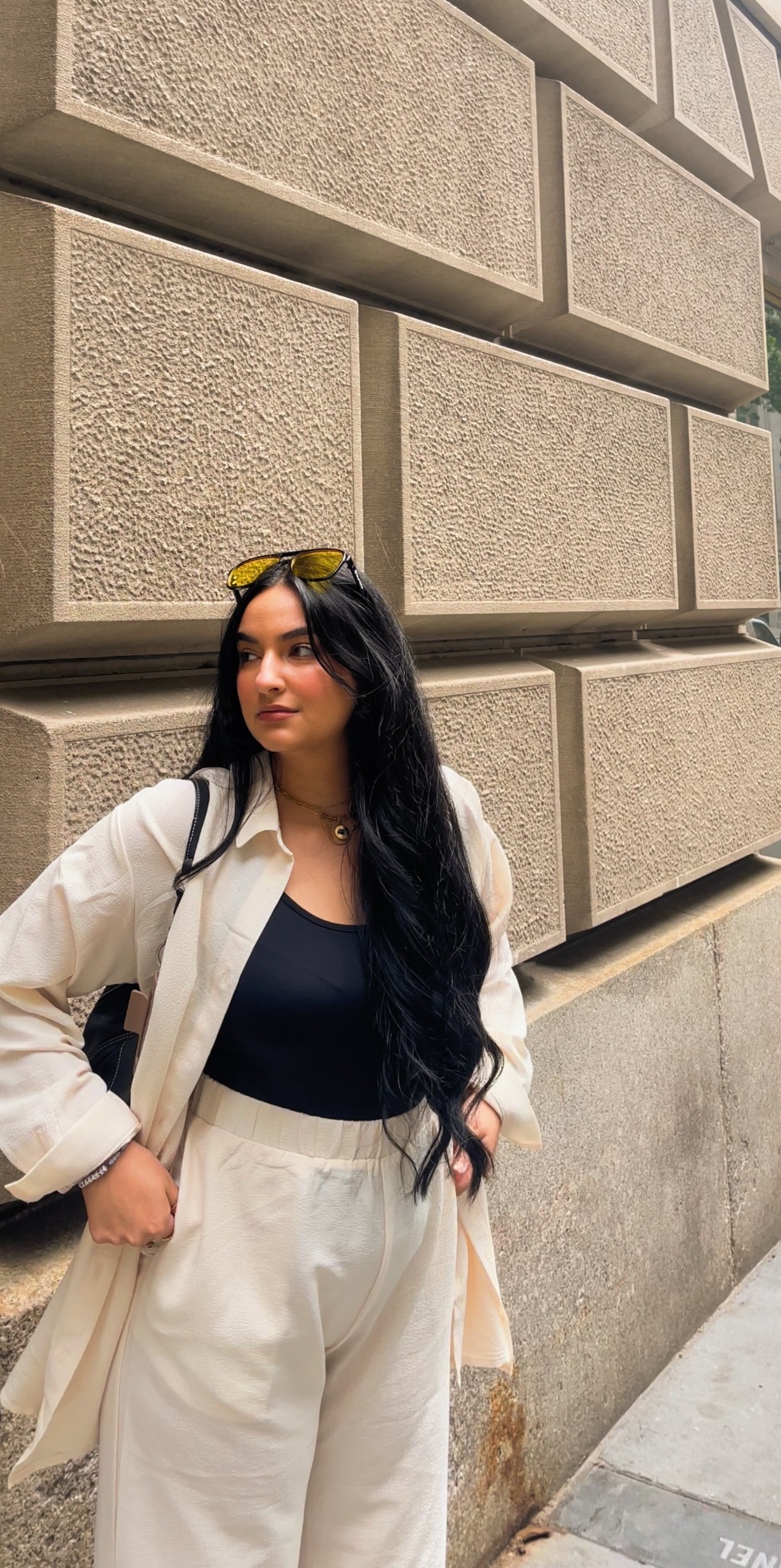 Safaa Salem in black and cream outfit with yellow lens sunglasses on her head