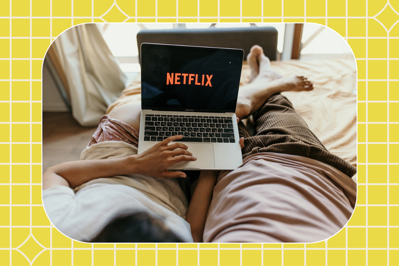 couple on bed watching netflix on laptop