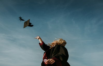 A woman throws her graduation cap in the sky.