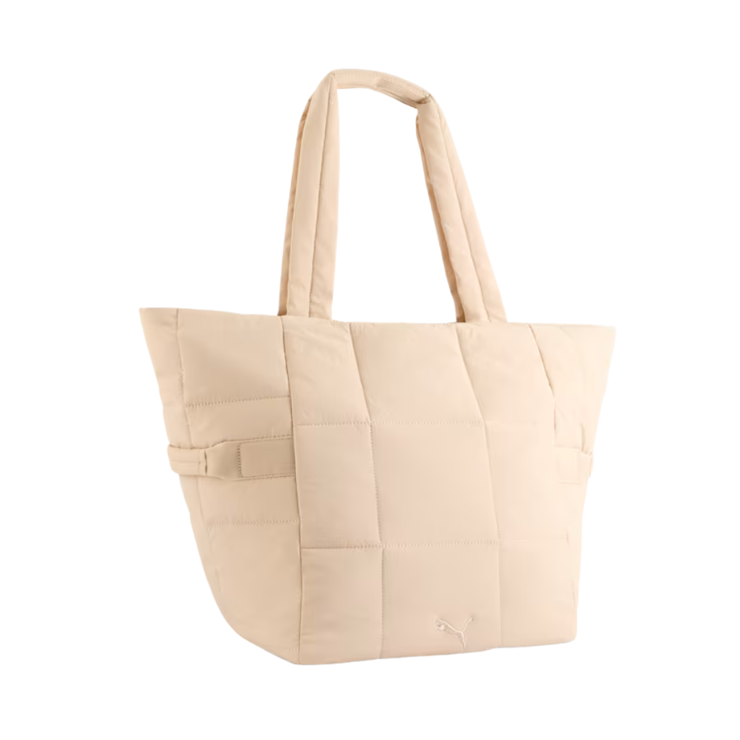 Cream-colored quilted tote bag with padded handles, featuring a stitched grid pattern. The design is minimalistic and stylish, conveying a sense of casual elegance.