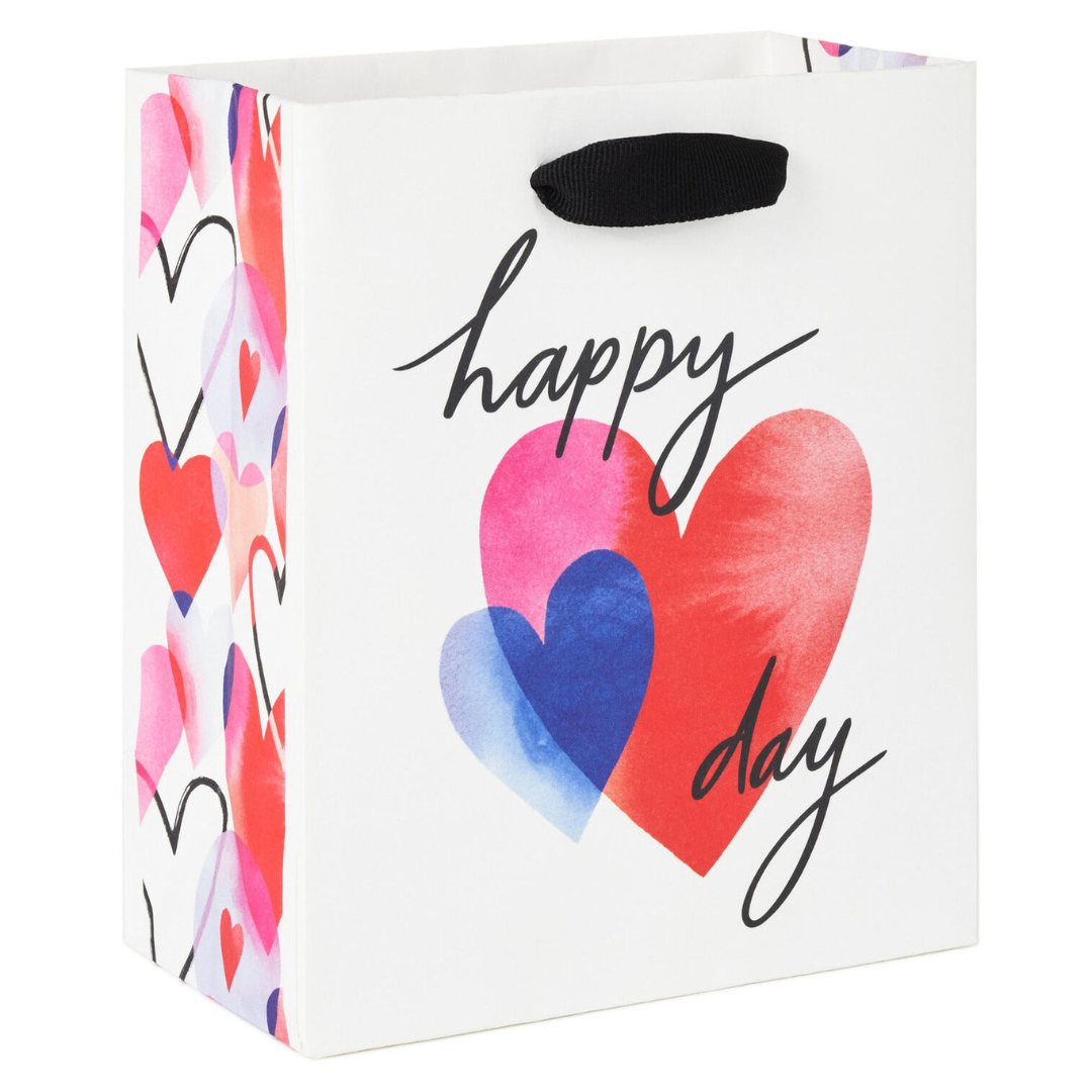white gift bag with black strap and heart illustrations that reads \