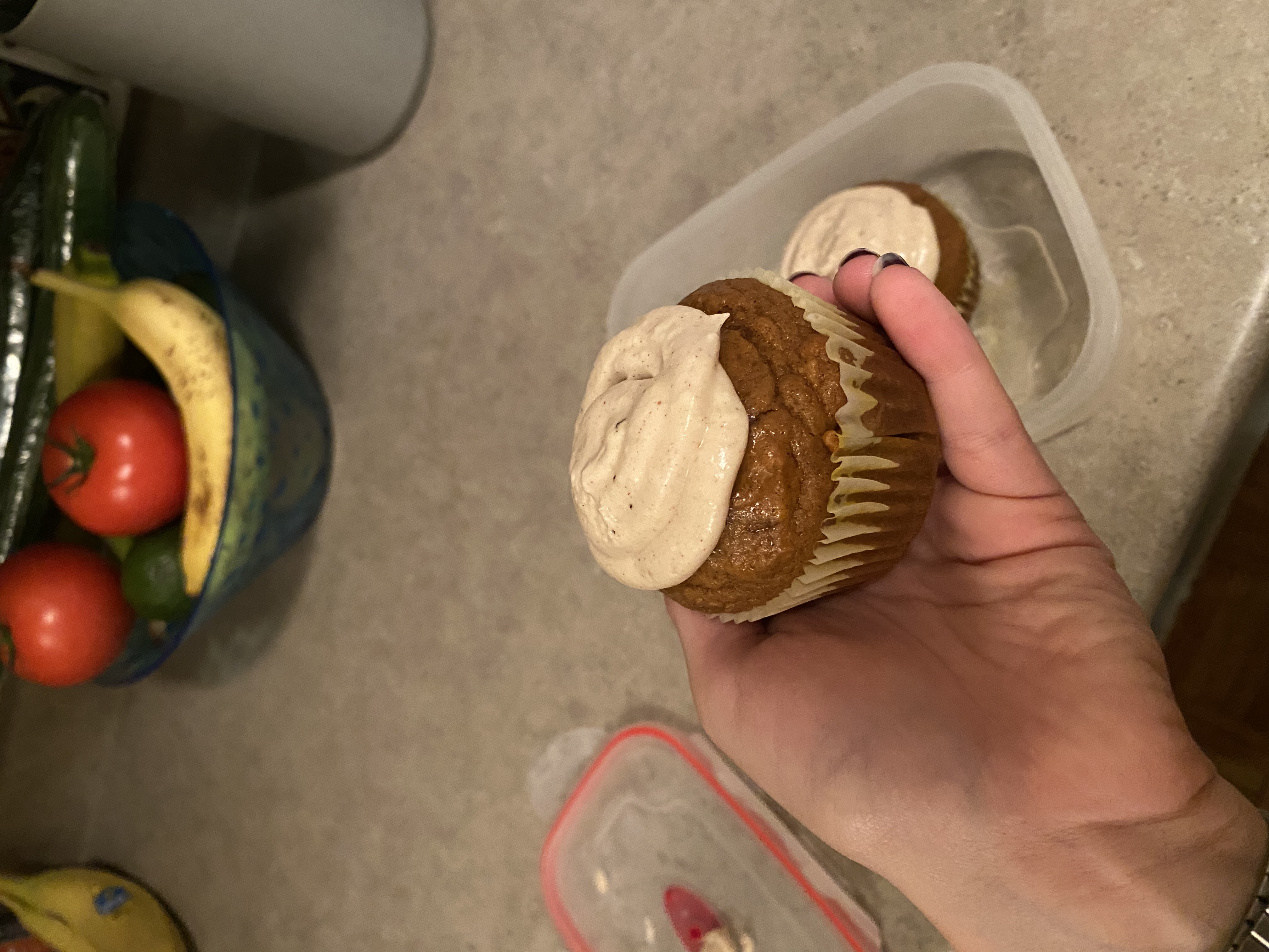 hand holding a muffin with icing on top