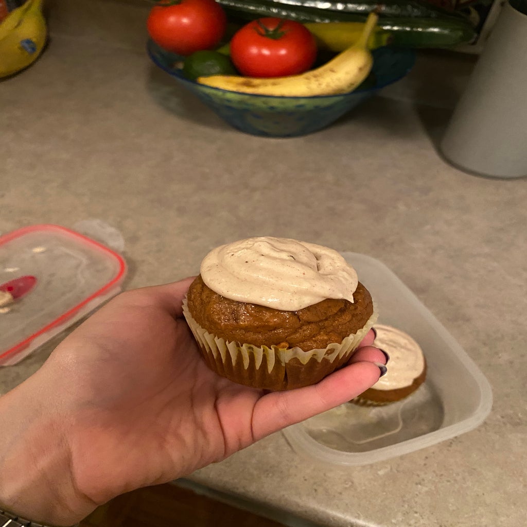 hand holding a muffin with icing on top