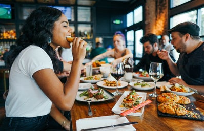 woman sitting at table taking a bite of food