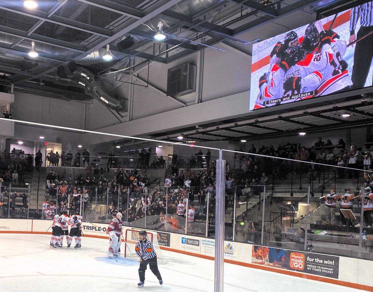 The RIT\'s Men Hockey team gather to hug and celebrate after scoring in a goal while the crowd cheers