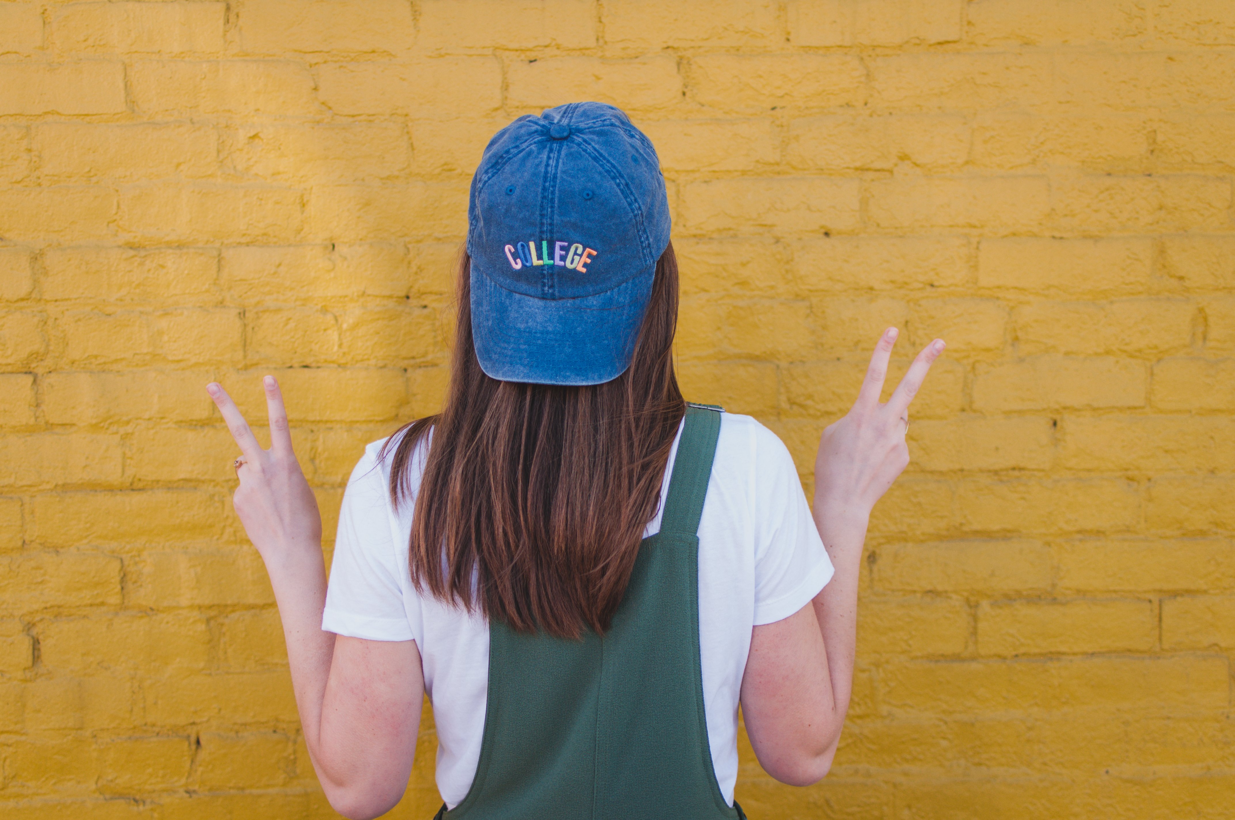 girl with blue college cap yellow wall