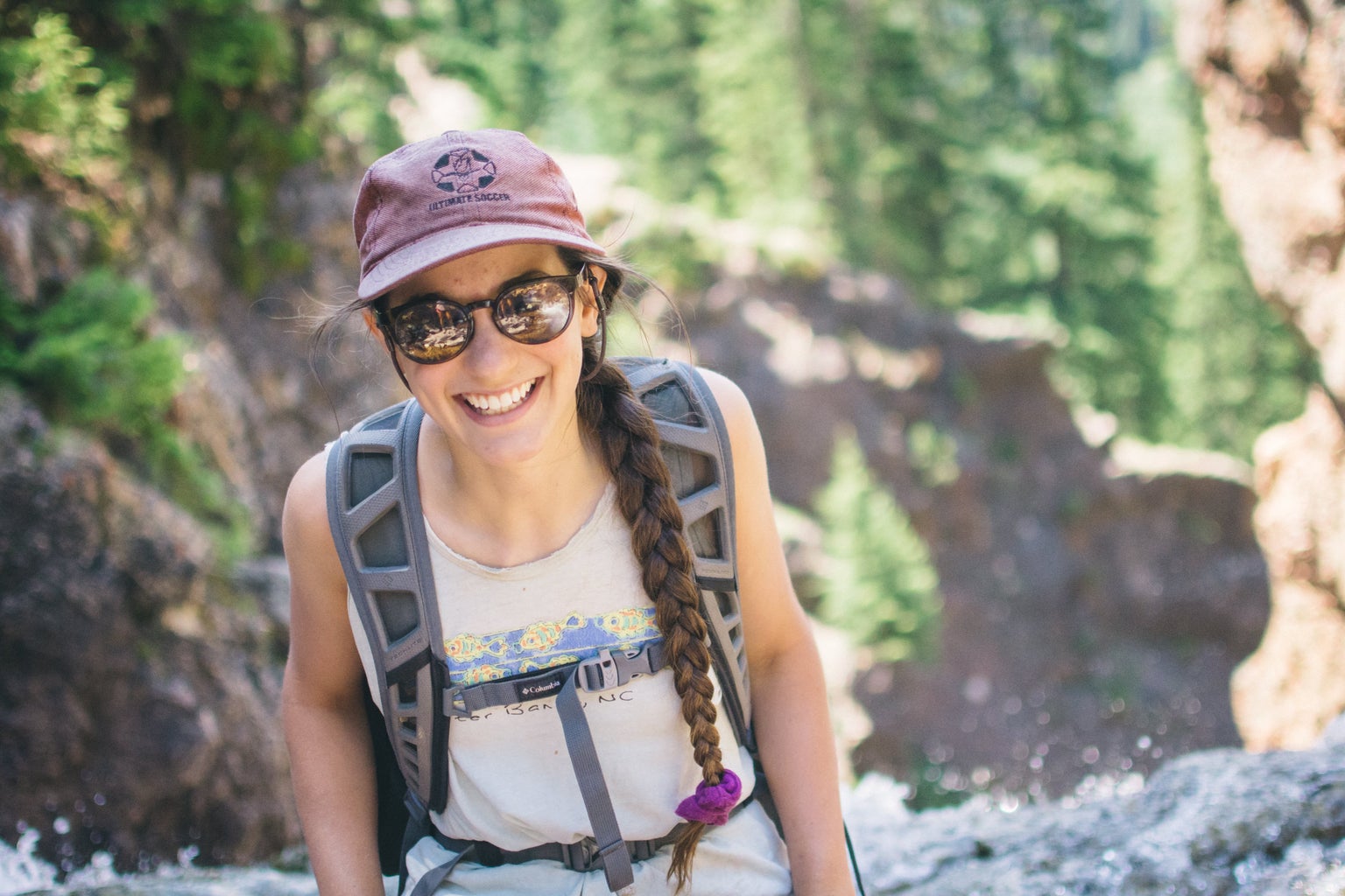 girl happy colorado travel hiking waterfall smile sunglasses hat