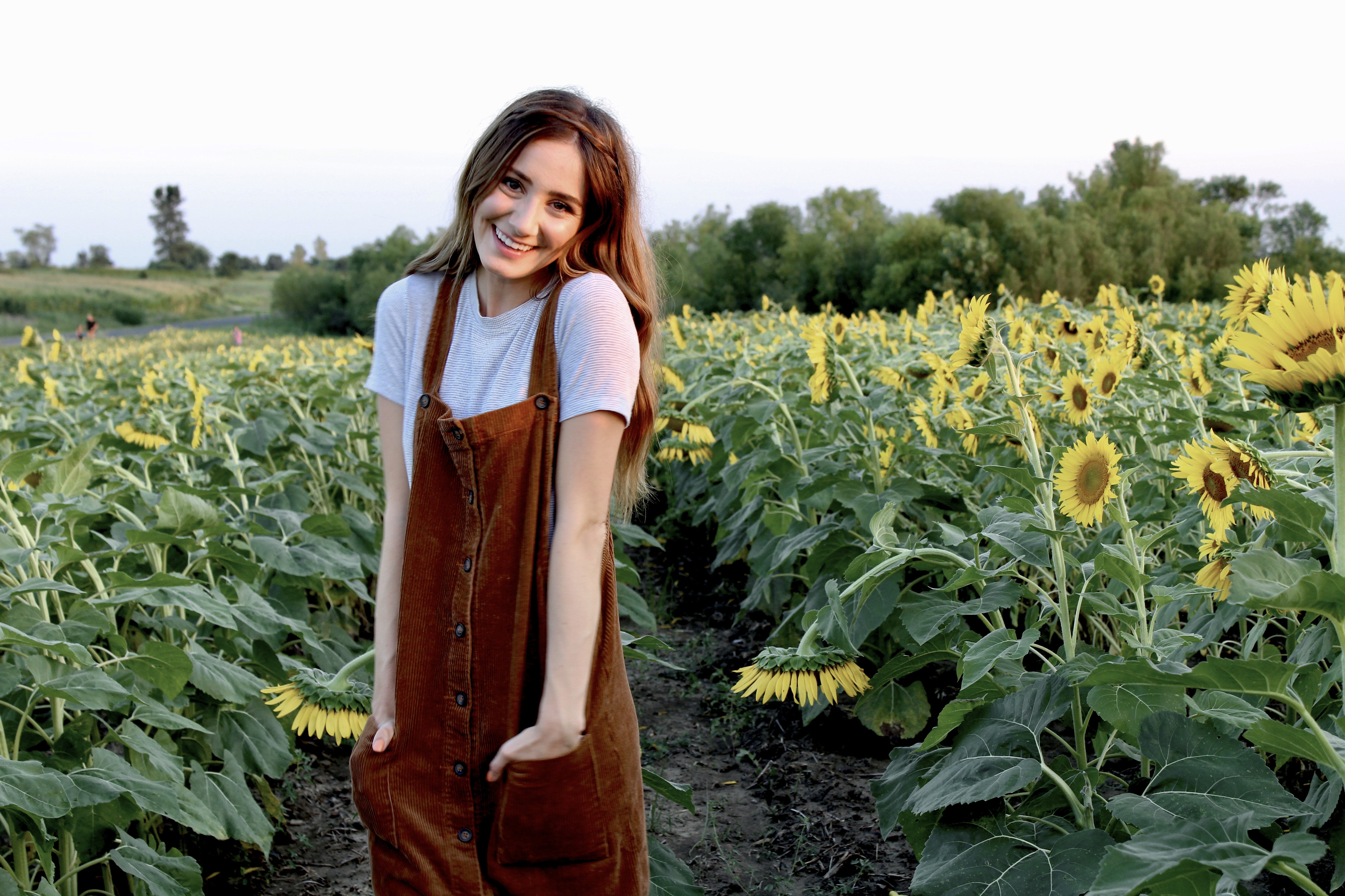 brunette happy girl sunflower field dress hands in pockets