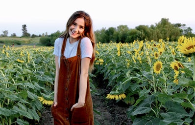 brunette happy girl sunflower field dress hands in pockets