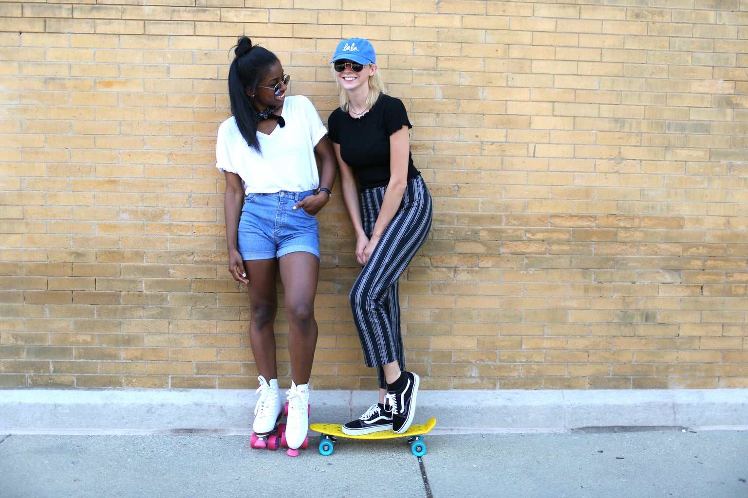 two girls friends baseball cap sunglasses skateboard roller skates happy