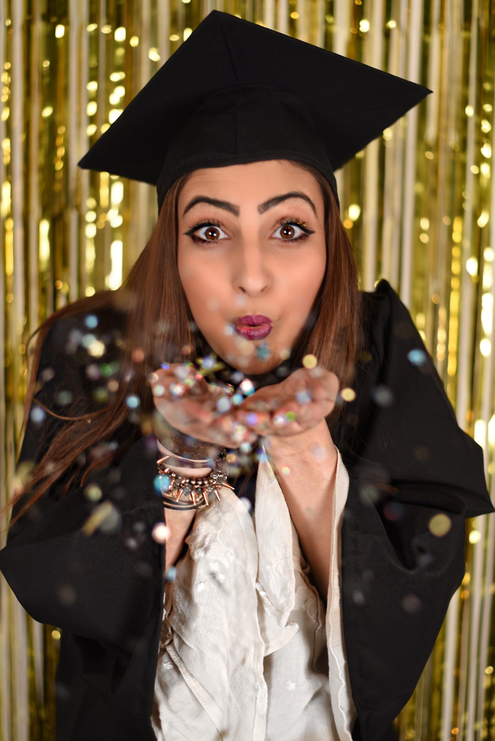 Graduate Blowing On Confetti