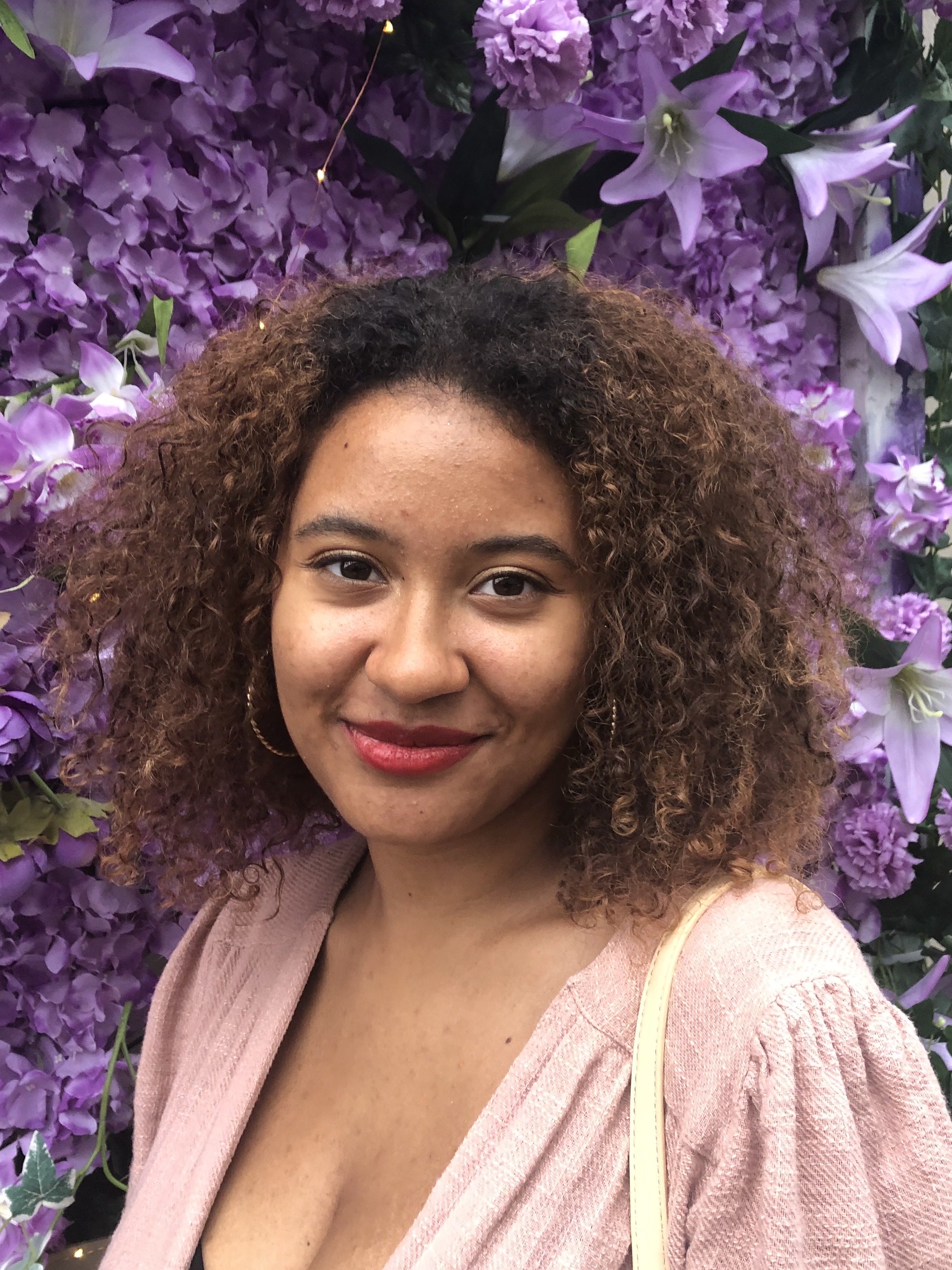 bi-racial girl in front of flowers smiling