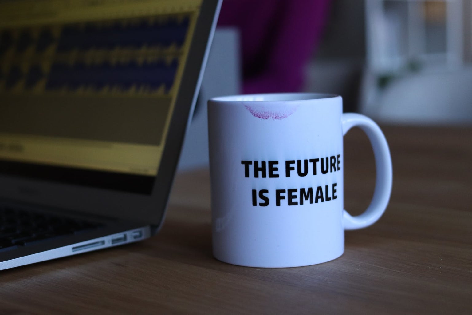 Laptop with white mug that says the future is female with a lipstick mark