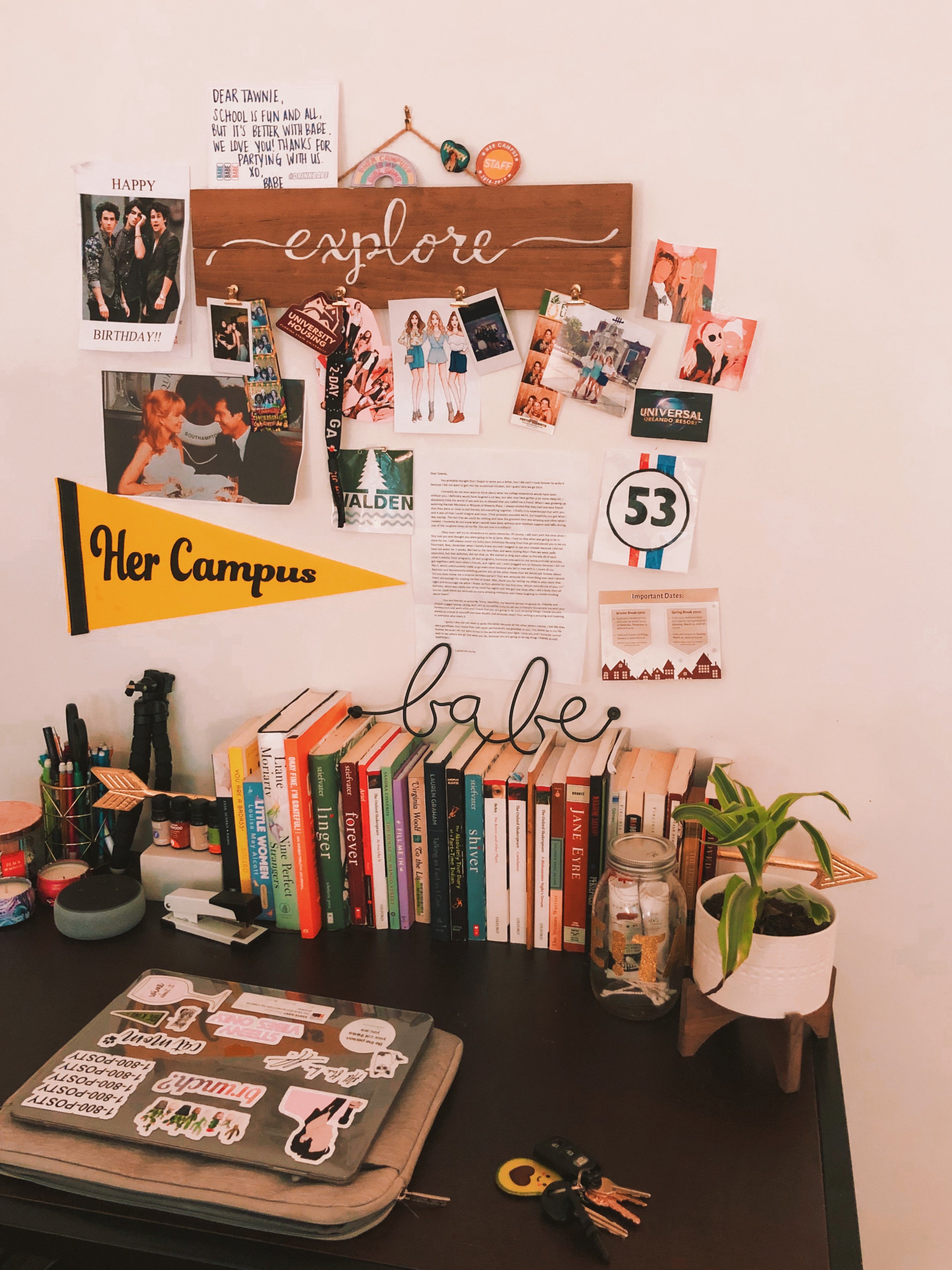A desk in a bedroom with keepsakes and decor hanging above it