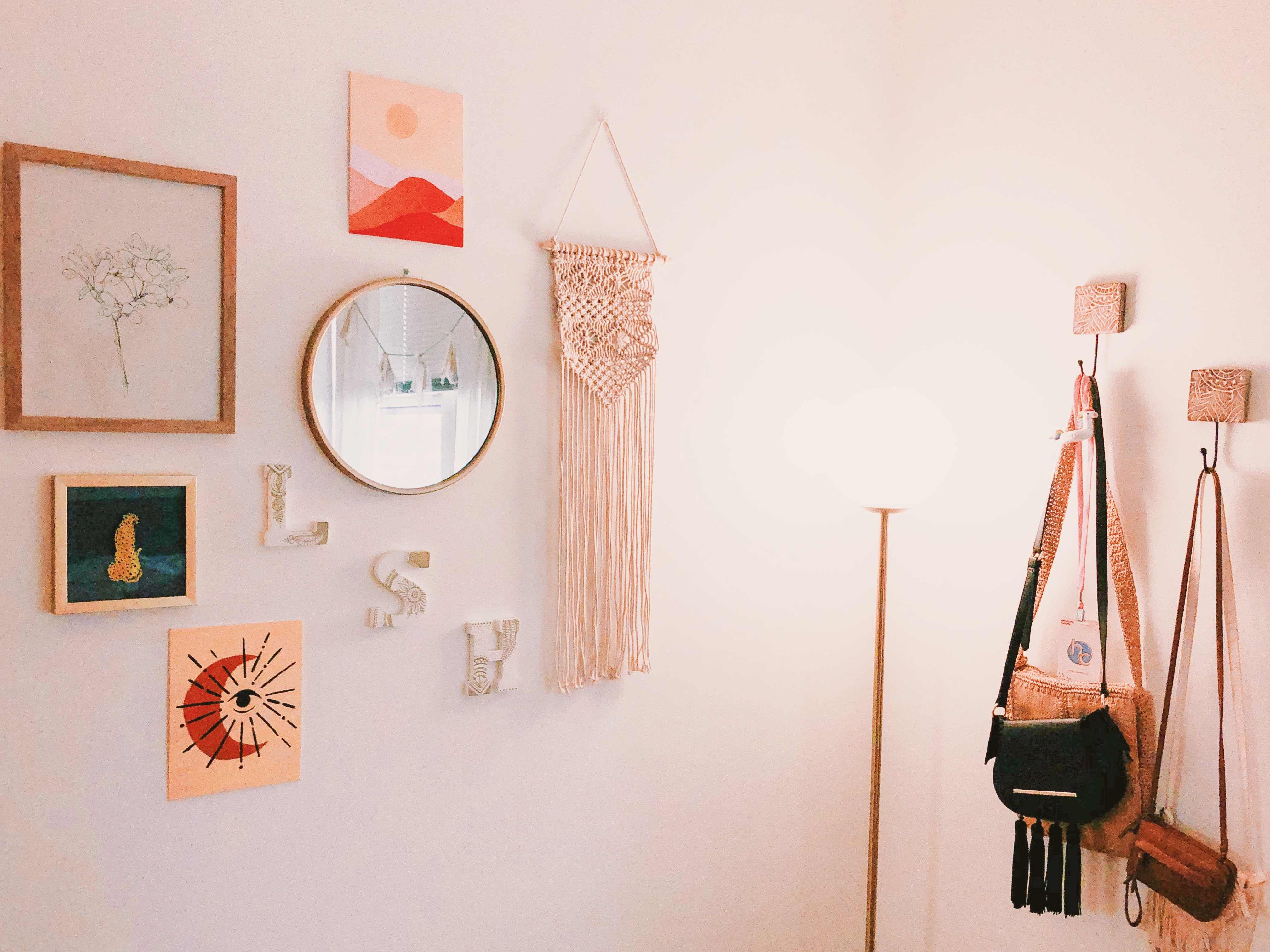 A decorated wall in a bedroom with pictures, mirrors and letters