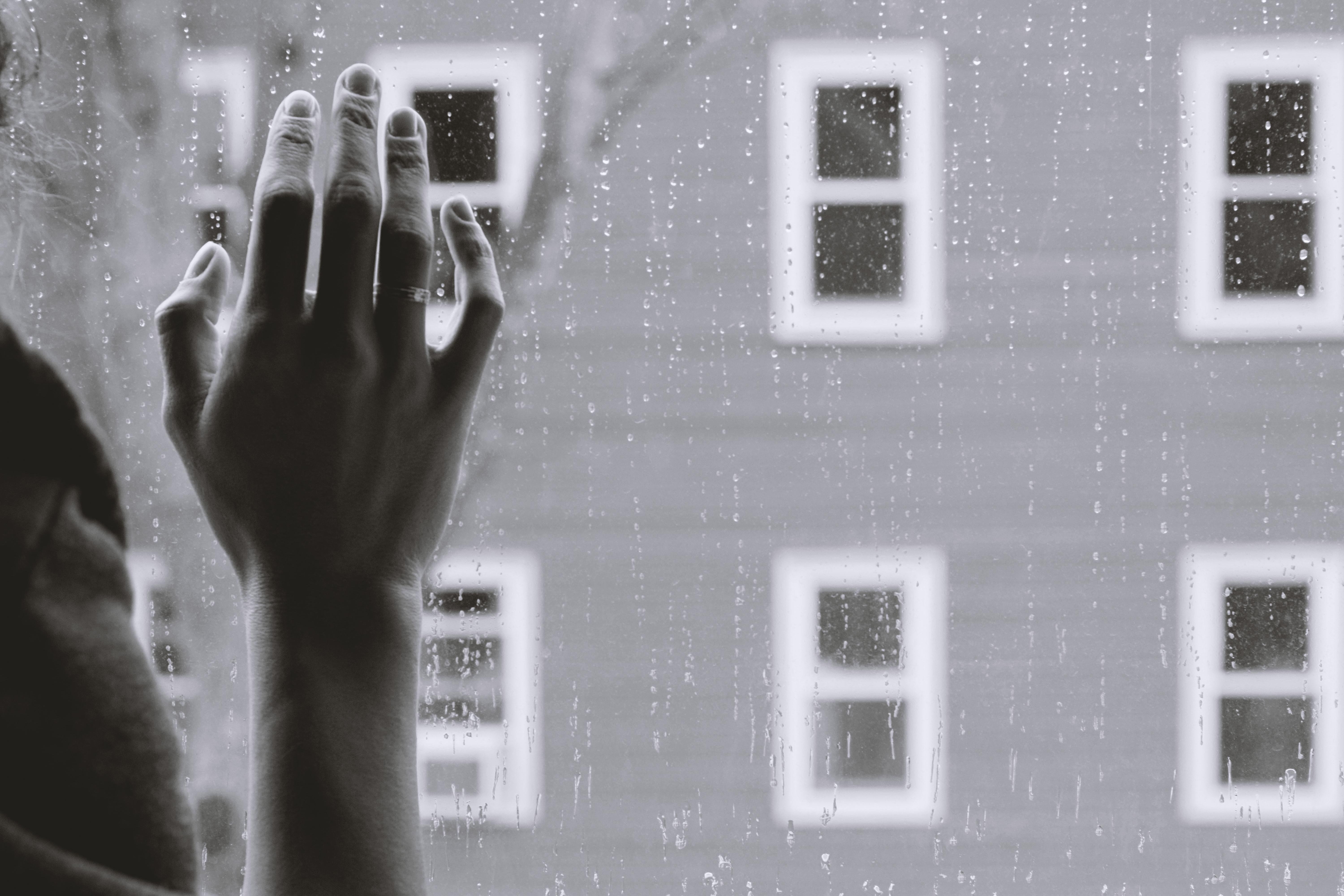 Woman\'s hand against window on rainy day