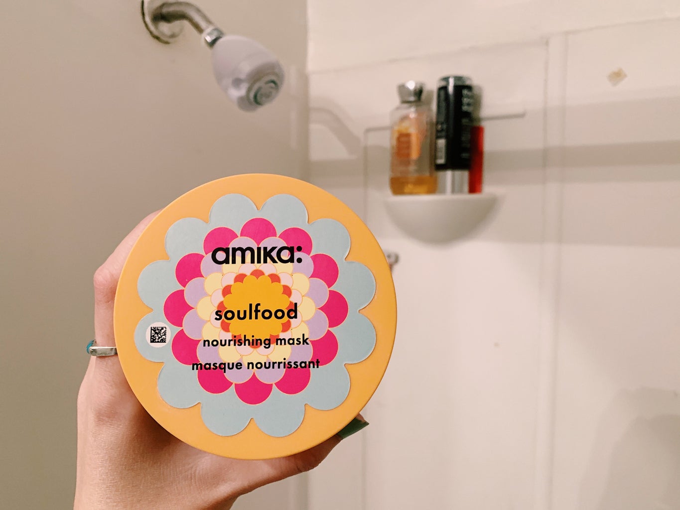 holding amika\'s nourishing hair mask in front of shower.