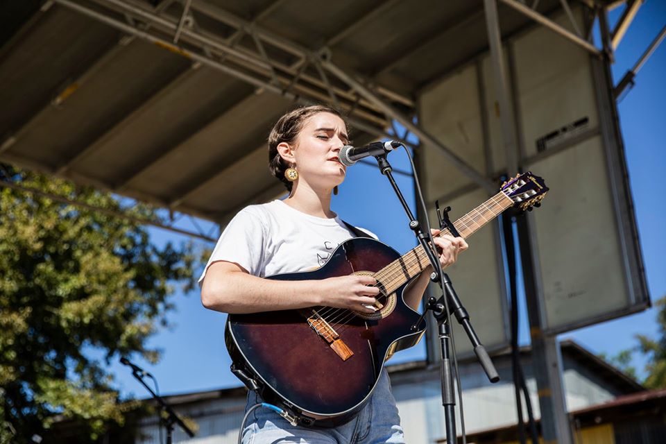 Girl in white shirt playing guitar and singing
