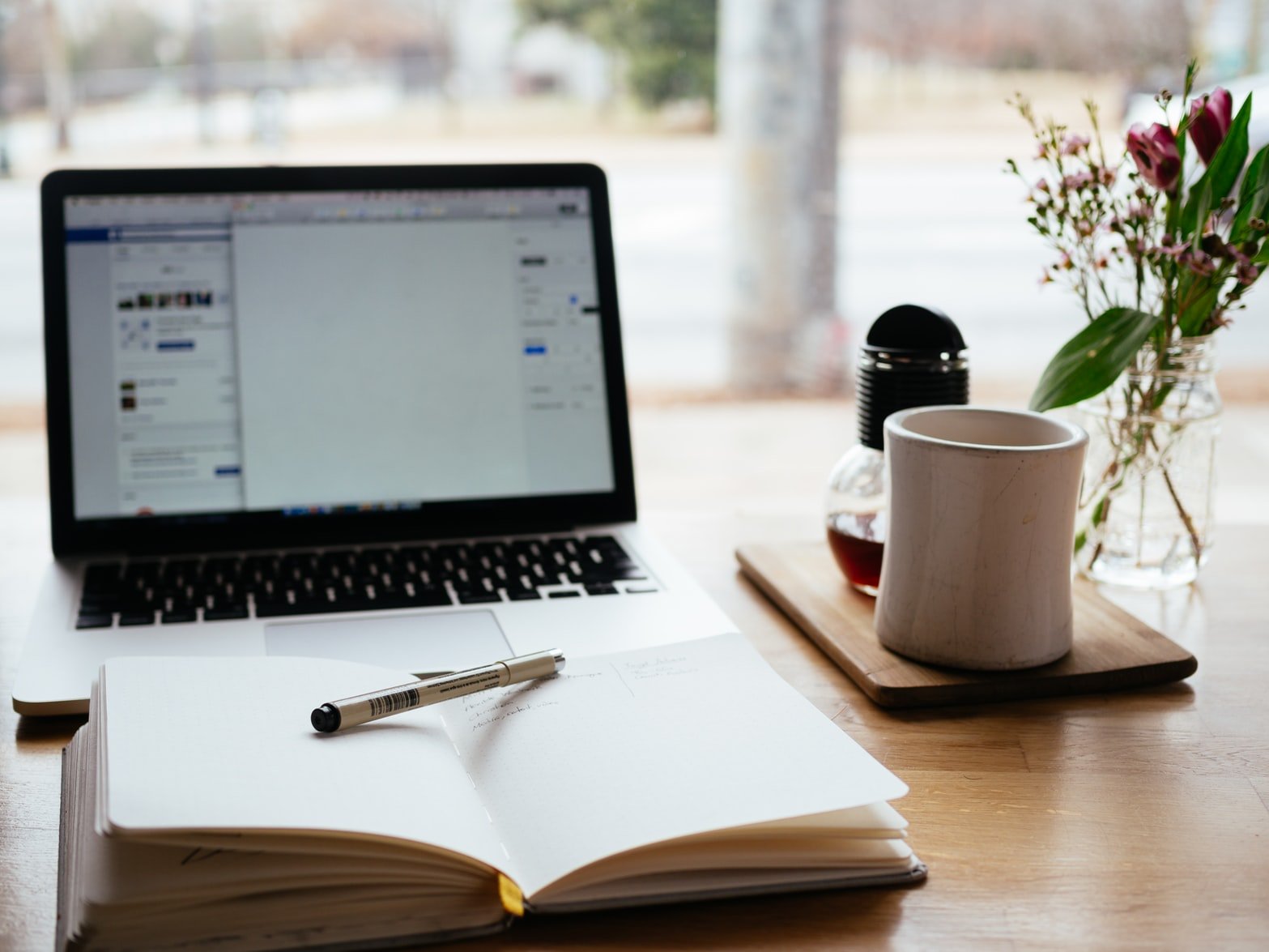 A desk with a computer, notebook, and tea