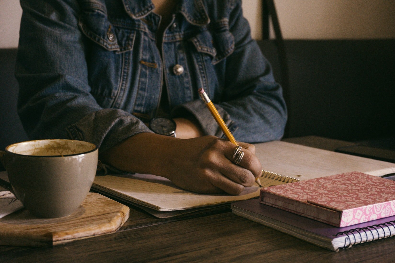 African American woman writing at a table with a cup of tea beside her