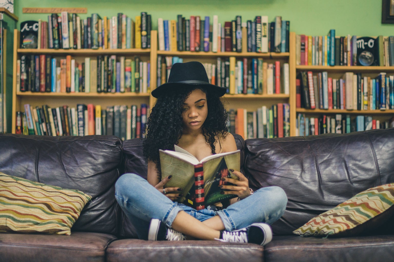 woman reading a book on a couch in a library