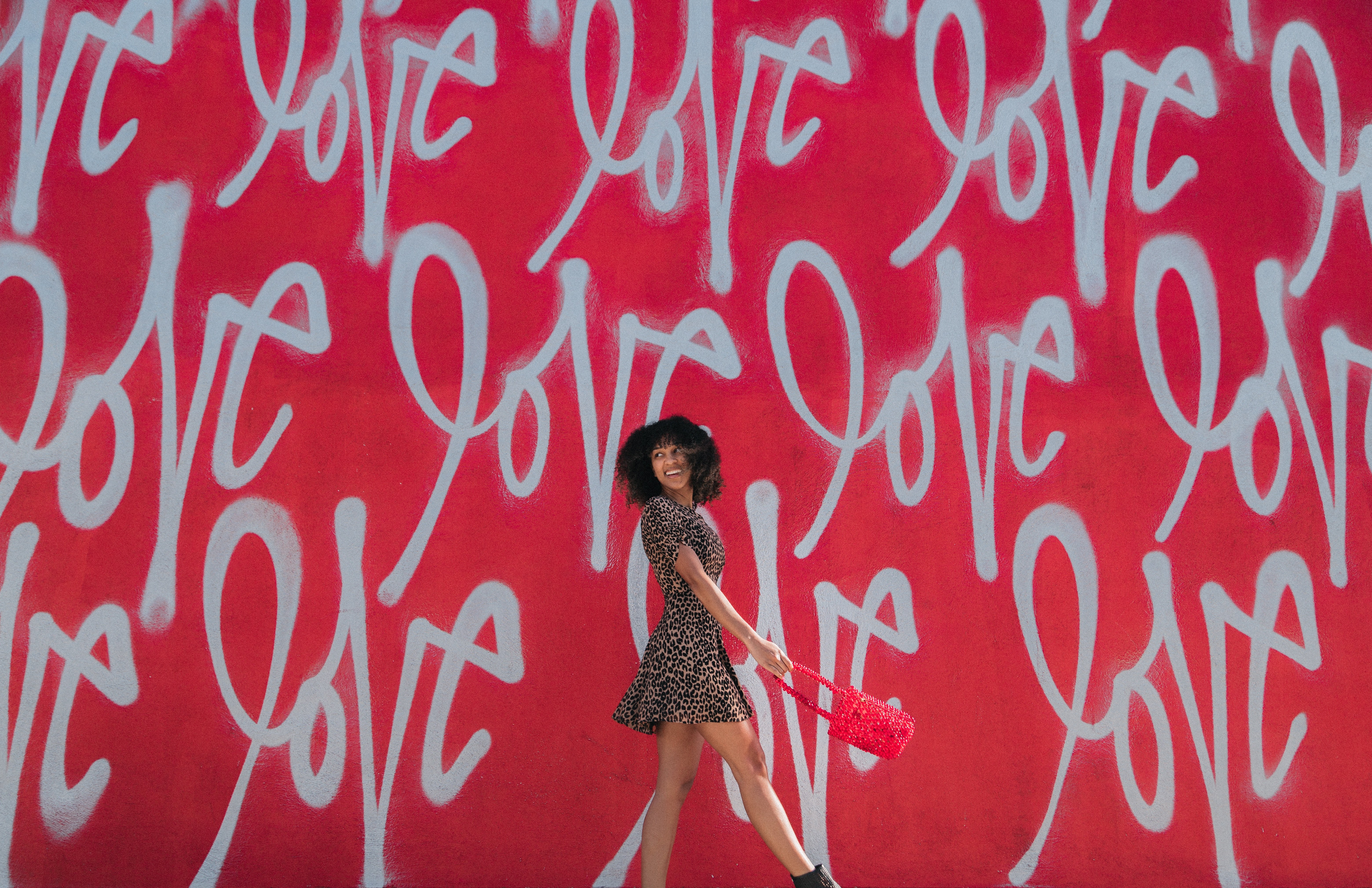 Girl standing in front of red wall that says \"love\"