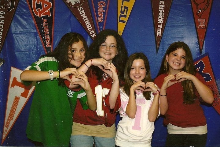 girls wearing sports team shirts holding up hand hearts