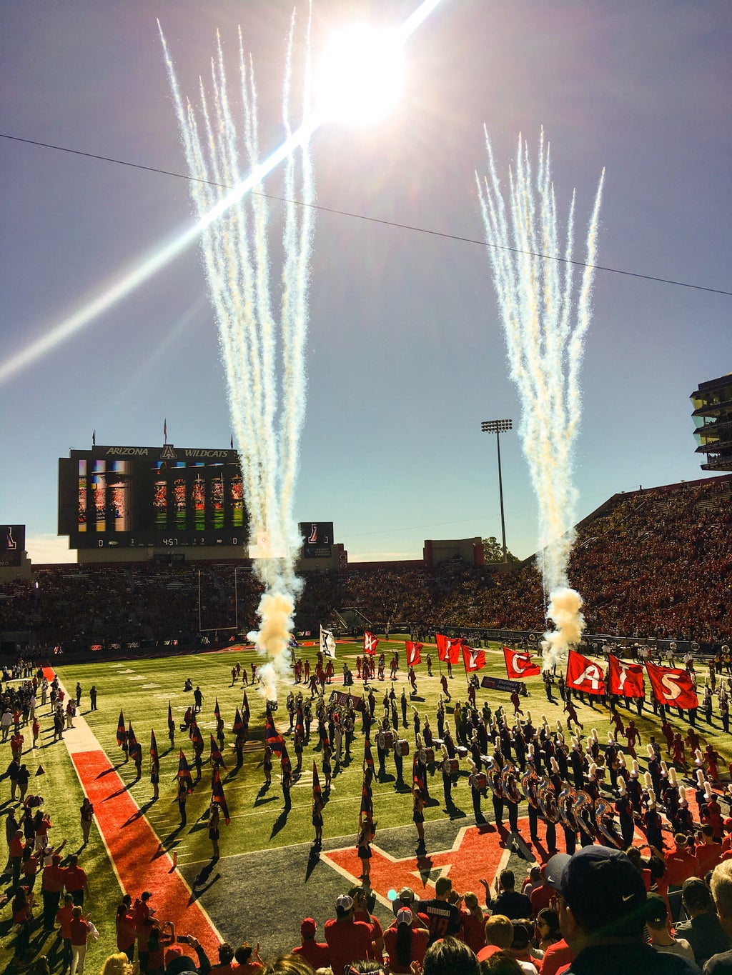 people standing at a stadium and a band marching