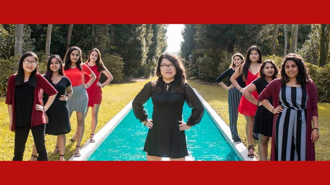 Jully standing in front of water with the rest of her executive board standing off to the sides of her