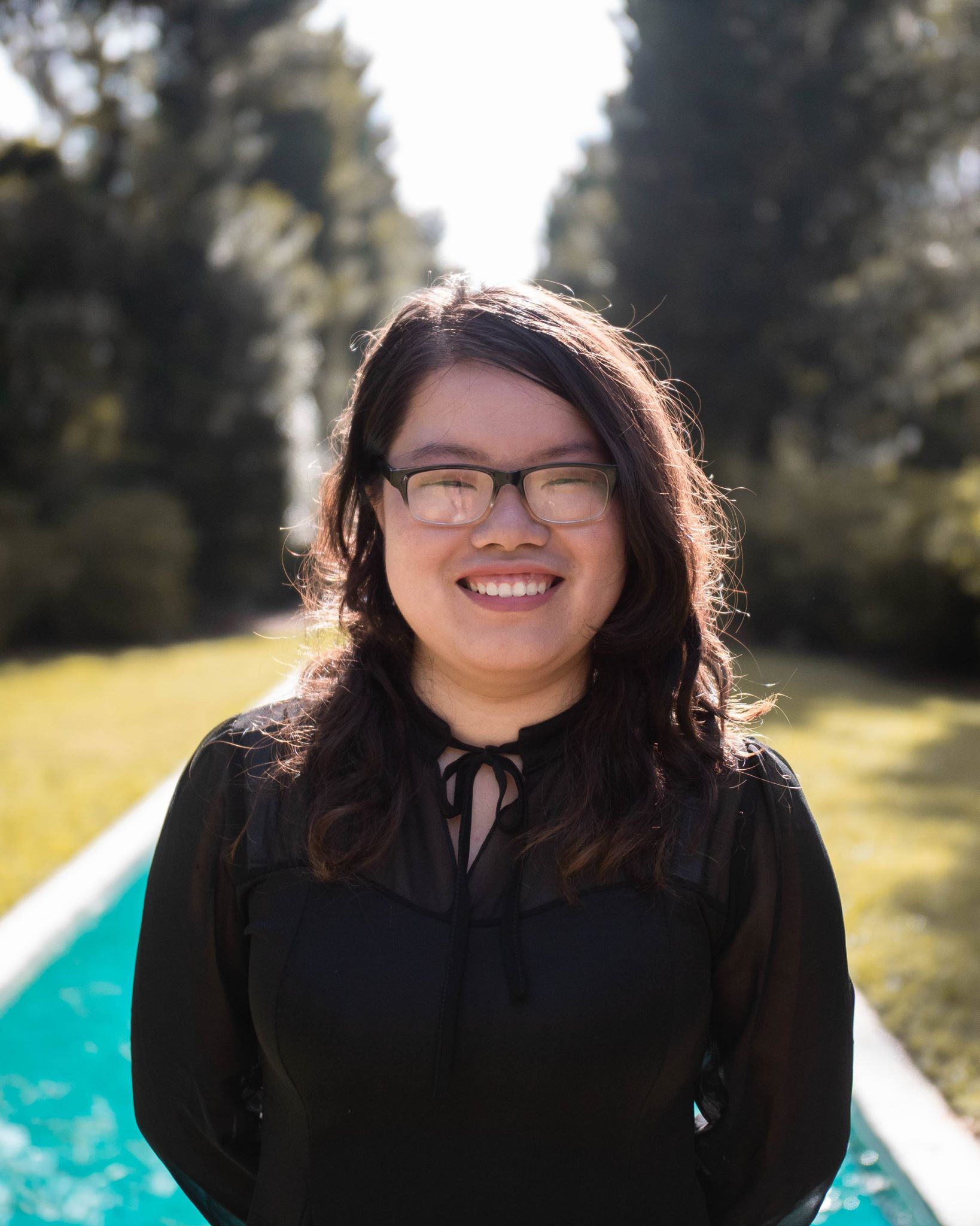 Jully standing in front of water/fountain and smiling