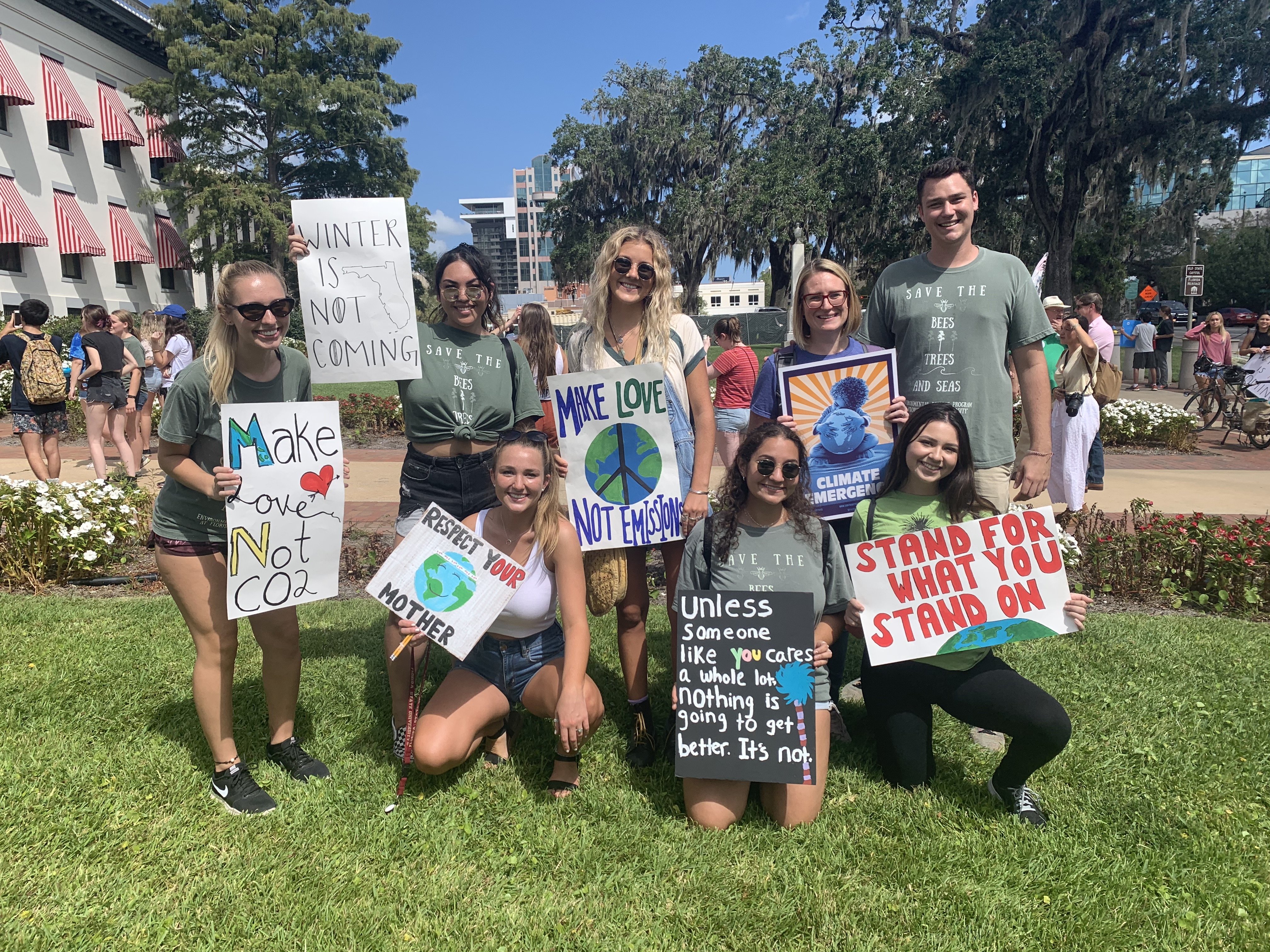 girl with friends outside on the grass holding up signs