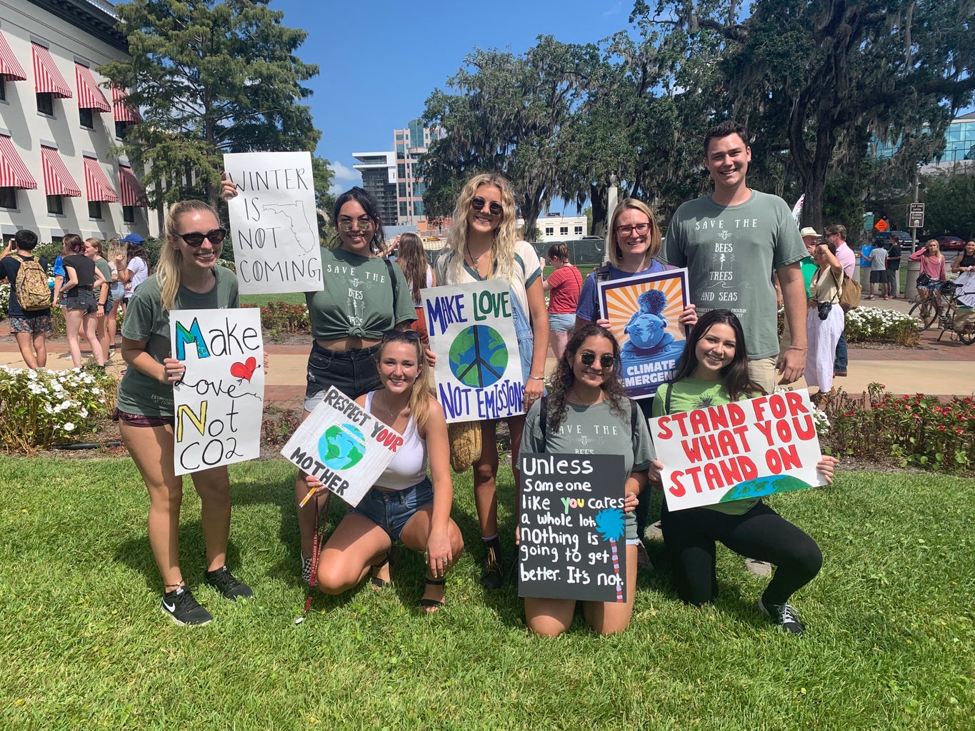 girl with friends outside on the grass holding up signs