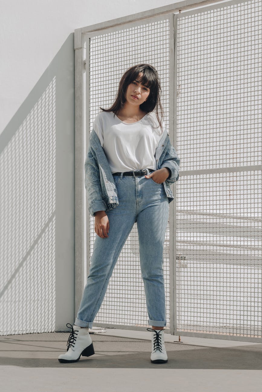 Woman standing against white background in denim jacket.