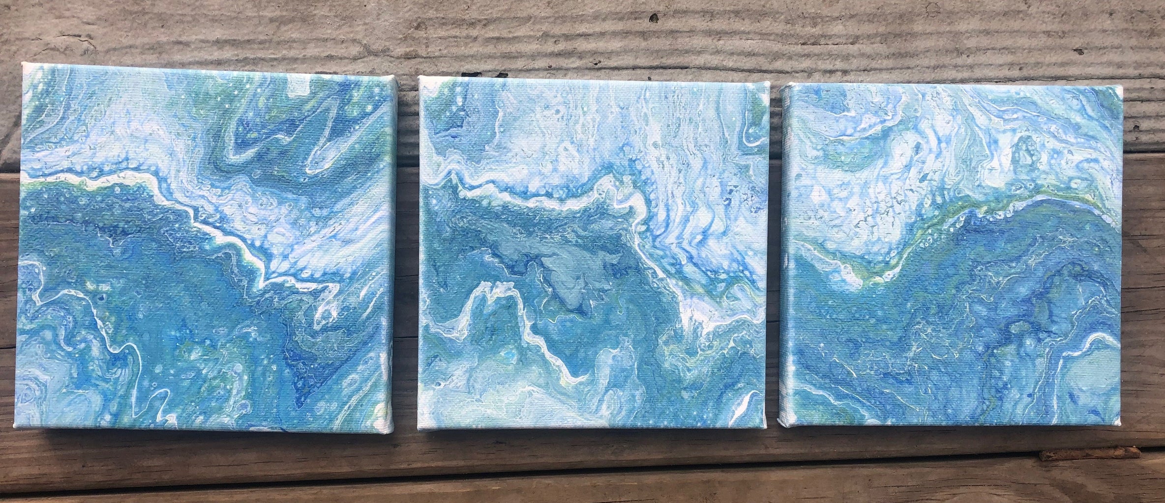 three blue paint pour canvases