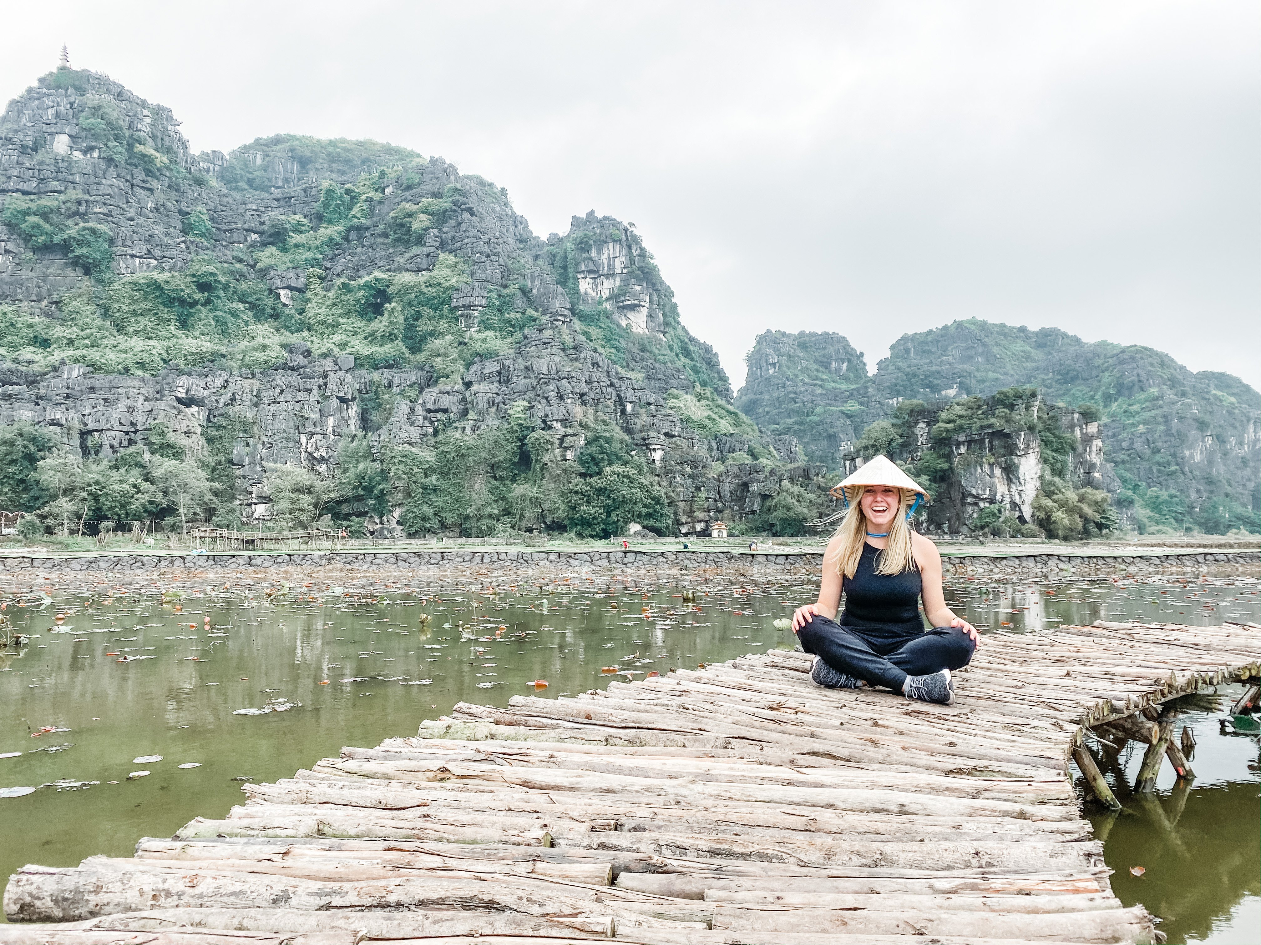 girl in hat sitting on pier in Vietnam