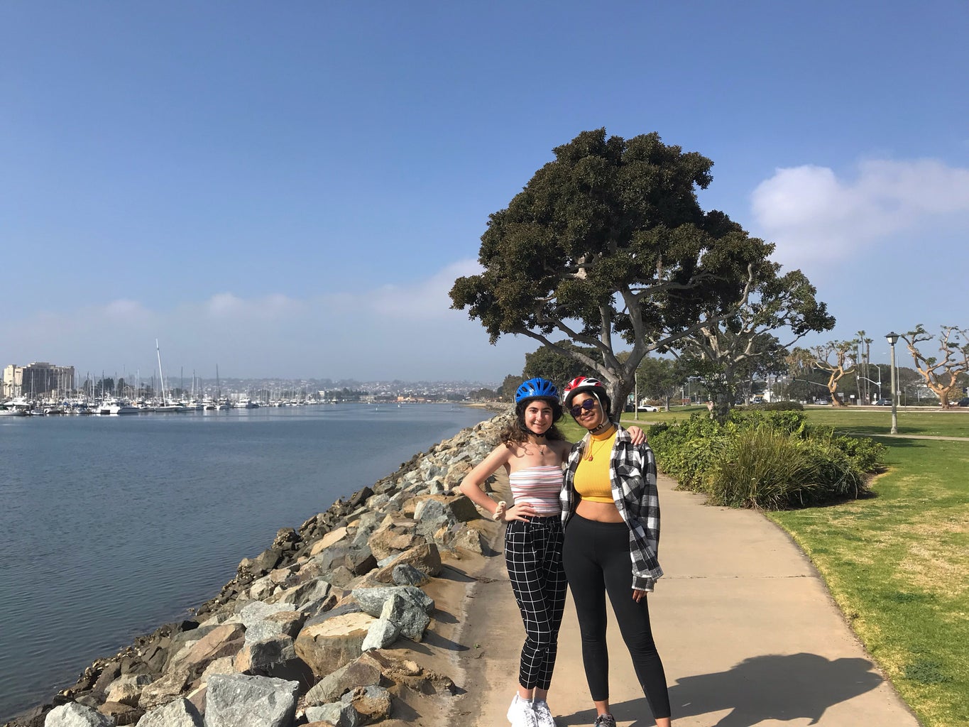 two girls standing on a path (near water) with bike helmets on