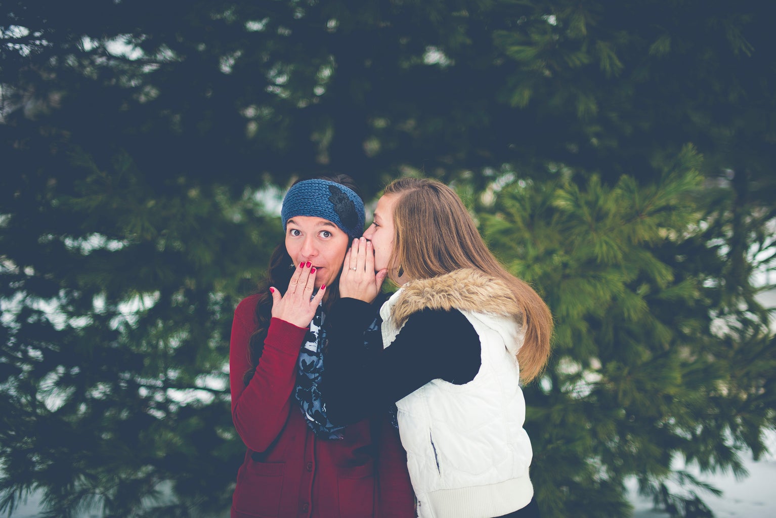 Woman whispering into other woman\'s ear