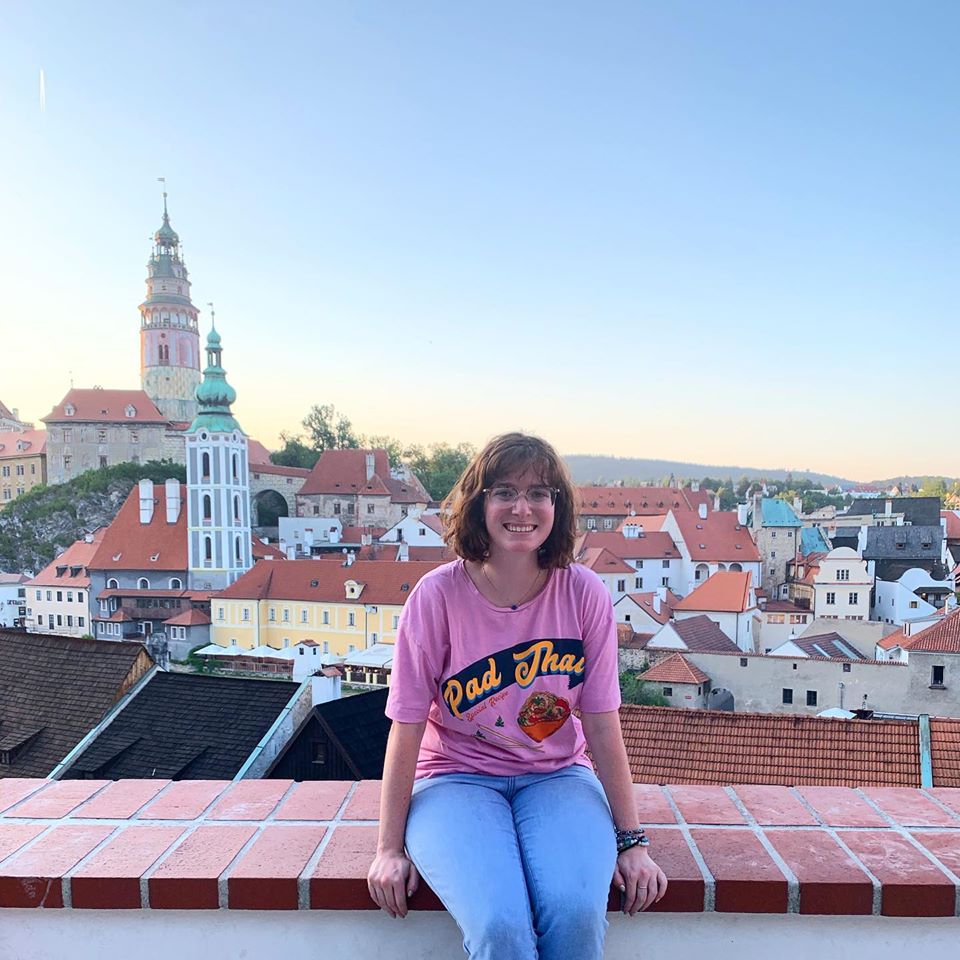 Woman in pink shirt sitting on brick ledge