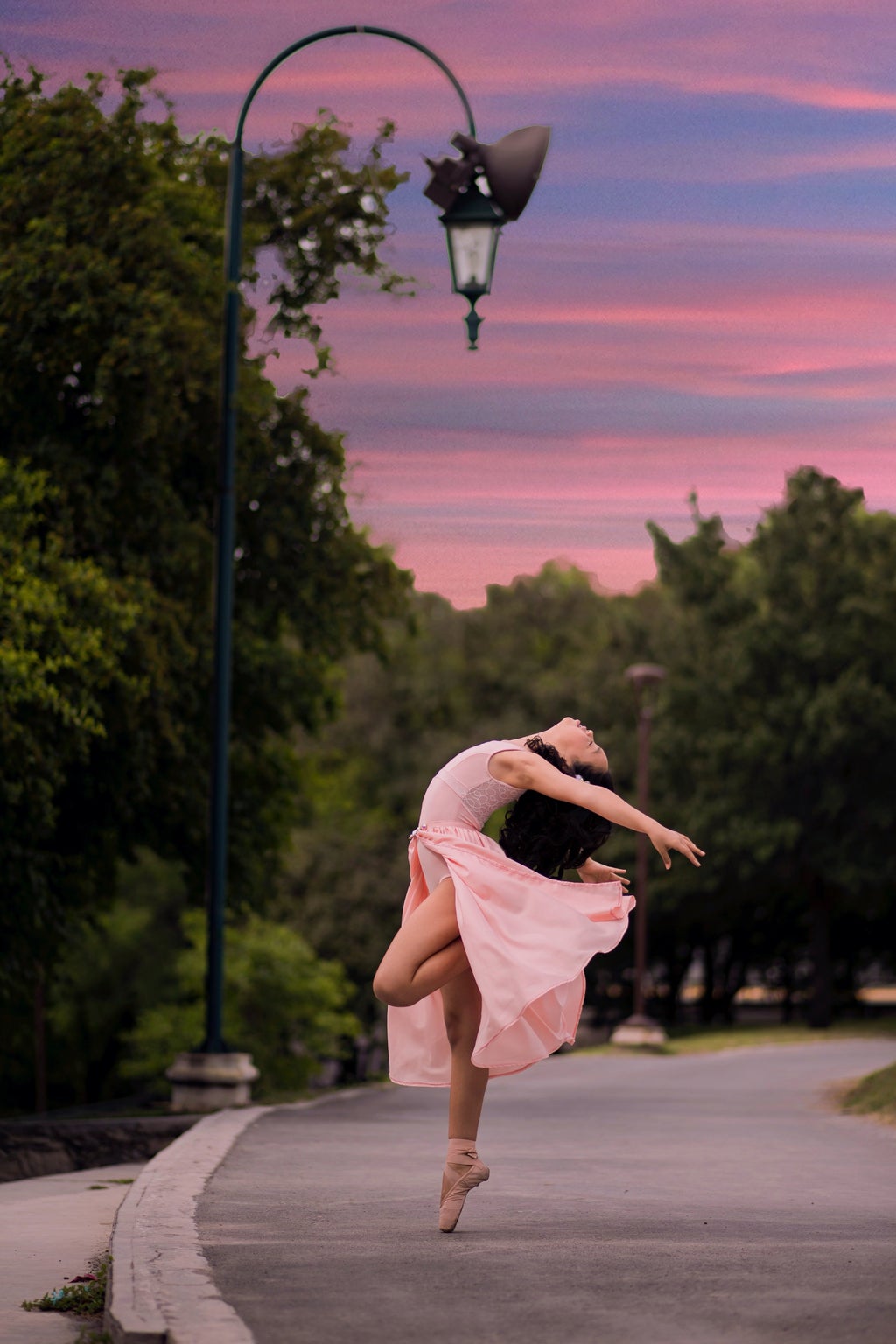 Ballet dancer on road beside streetlamp during sunset